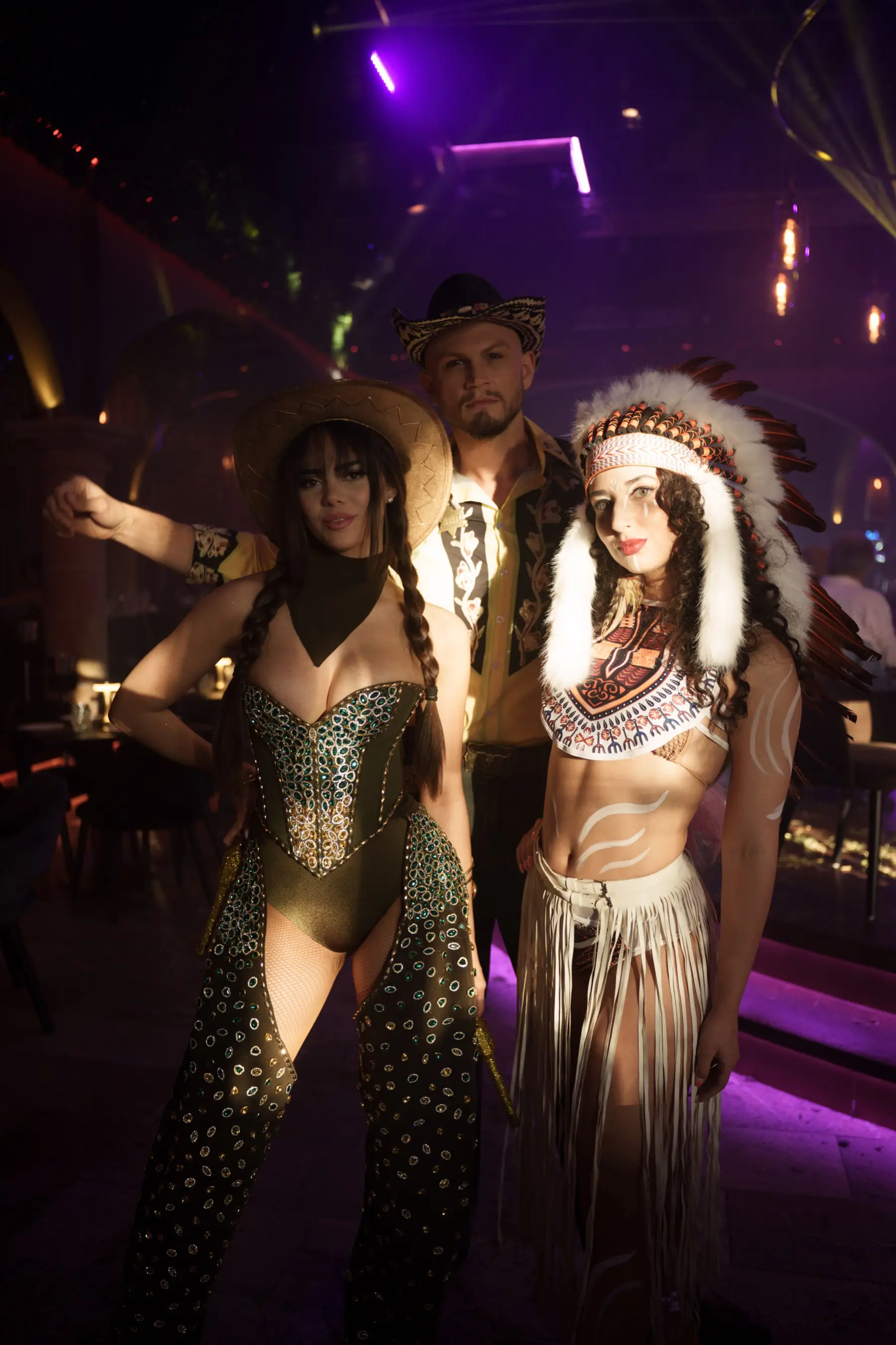 Guests posing with themed performers – Group photo of guests with rodeo-inspired entertainers dressed in glamorous western and drag outfits.