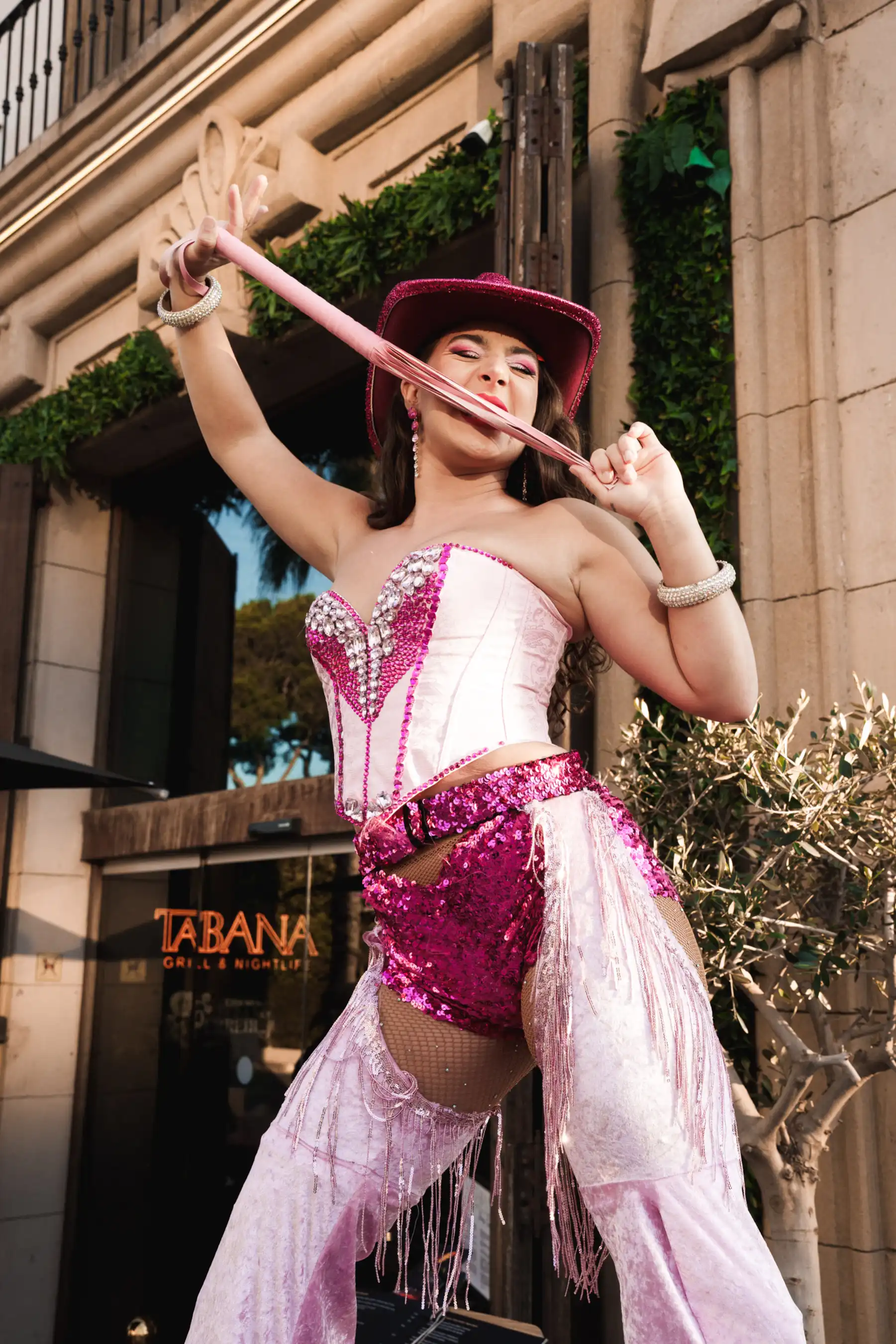 Performer in pink cowboy outfit – Entertainer in a sparkling pink and white western costume posing outside the venue.