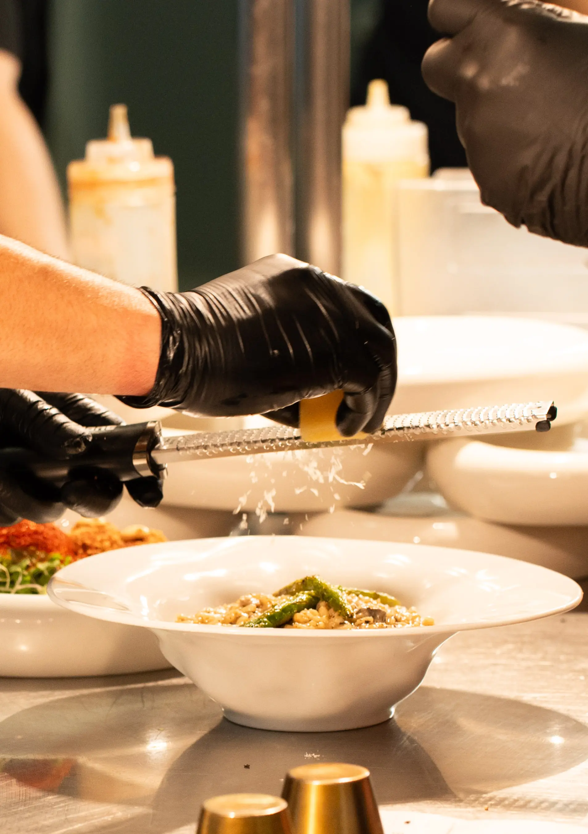 Chef grating cheese over dish – Chef finishing a fine dining plate with fresh parmesan, showcasing the event’s gourmet menu.
