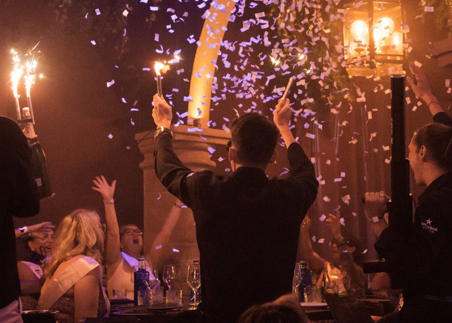 A lively party scene with a group of people celebrating, surrounded by colorful confetti in a festive atmosphere.