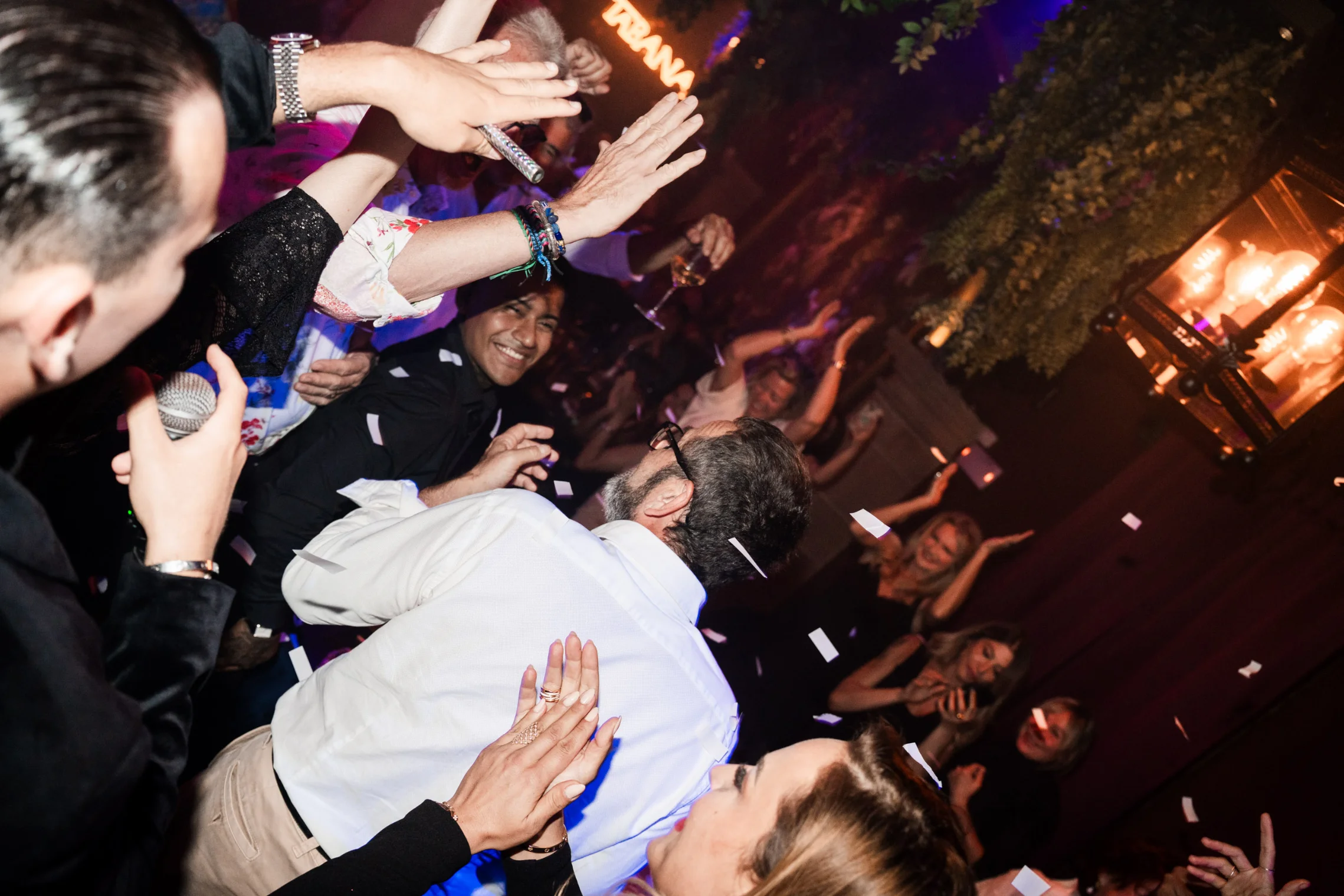 A lively group of people at a party, hands raised in excitement, enjoying the vibrant atmosphere of Playa de Palma.