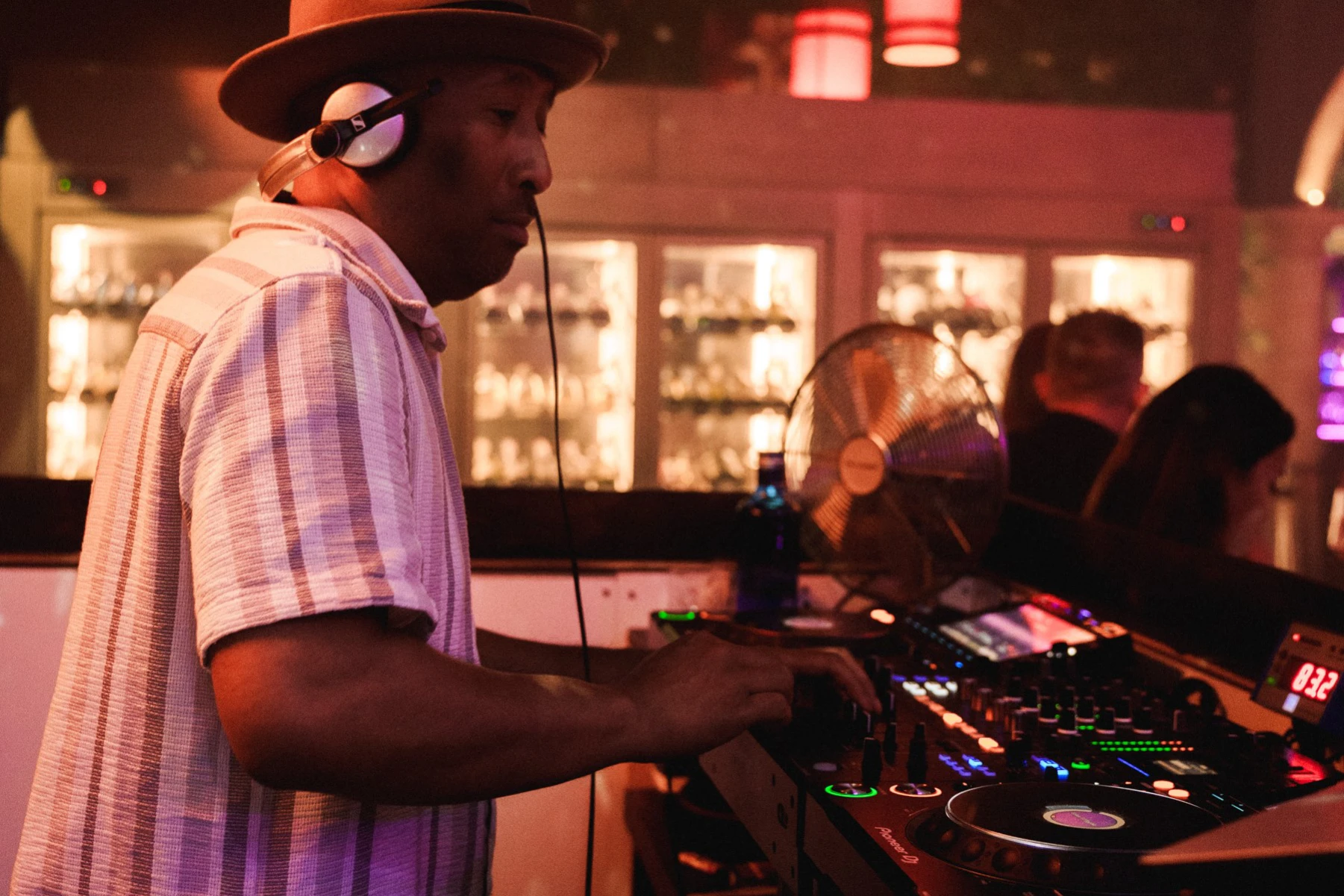 DJ in a hat and shirt playing music at a vibrant Tabana show party, energizing the crowd.