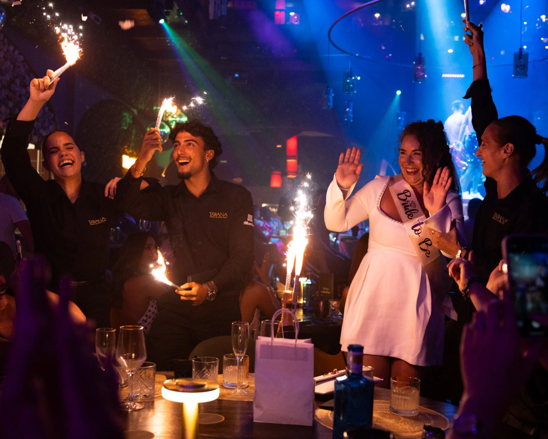 Despedida de soltera en Tabana, Playa de Palma, Mallorca. novia con bengalas y personal de Tabana durante una cena de cumpleaños en grupo