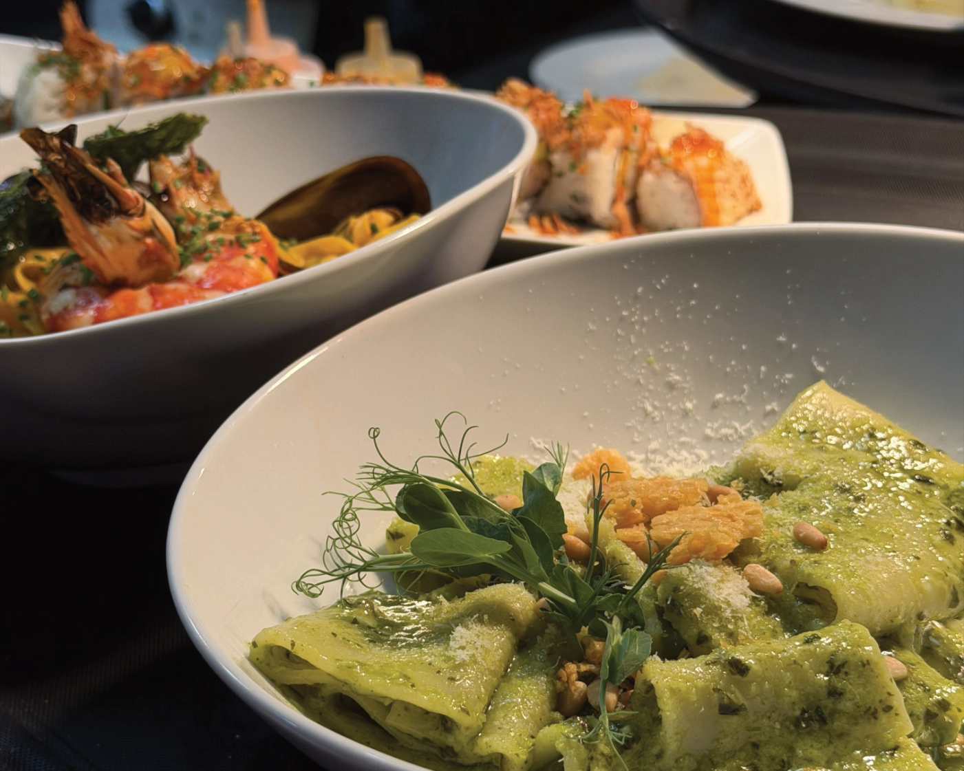 Pasta paccheri al pesto en primer plano, servida junto a pasta de marisco y platos de sushi en Tabana Playa de Palma.