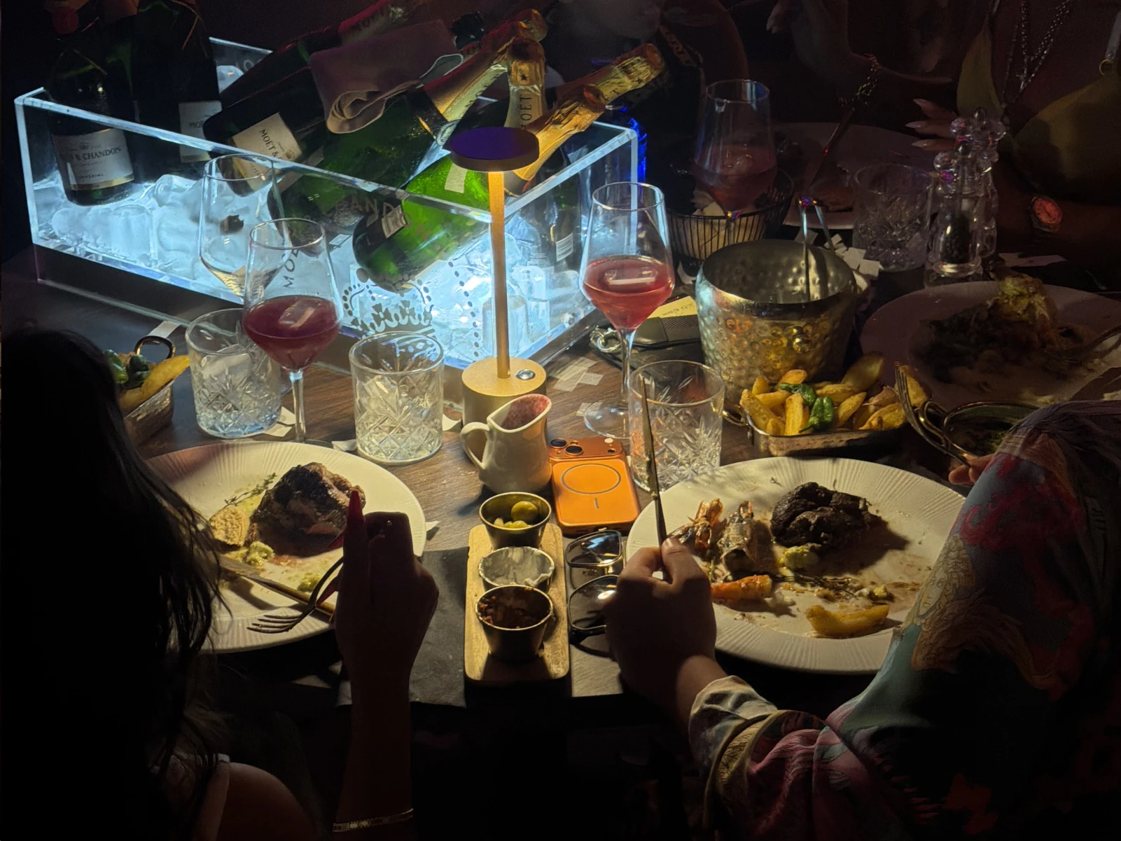 Clientes cenando junto a una cubitera iluminada con botellas de champán en Tabana, Playa de Palma.