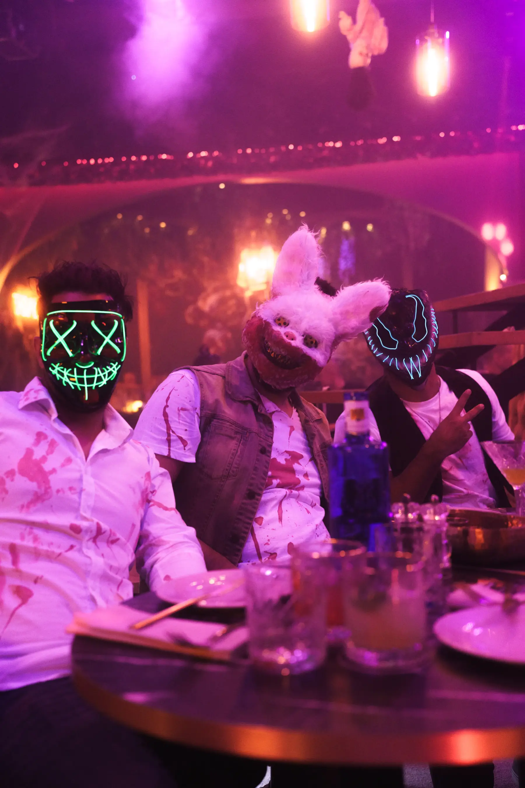 Three guests wearing Halloween masks at a table with drinks at Tabana in Playa de Palma