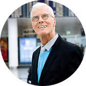 Porträtfoto eines lächelnden älteren Mannes im Anzug.