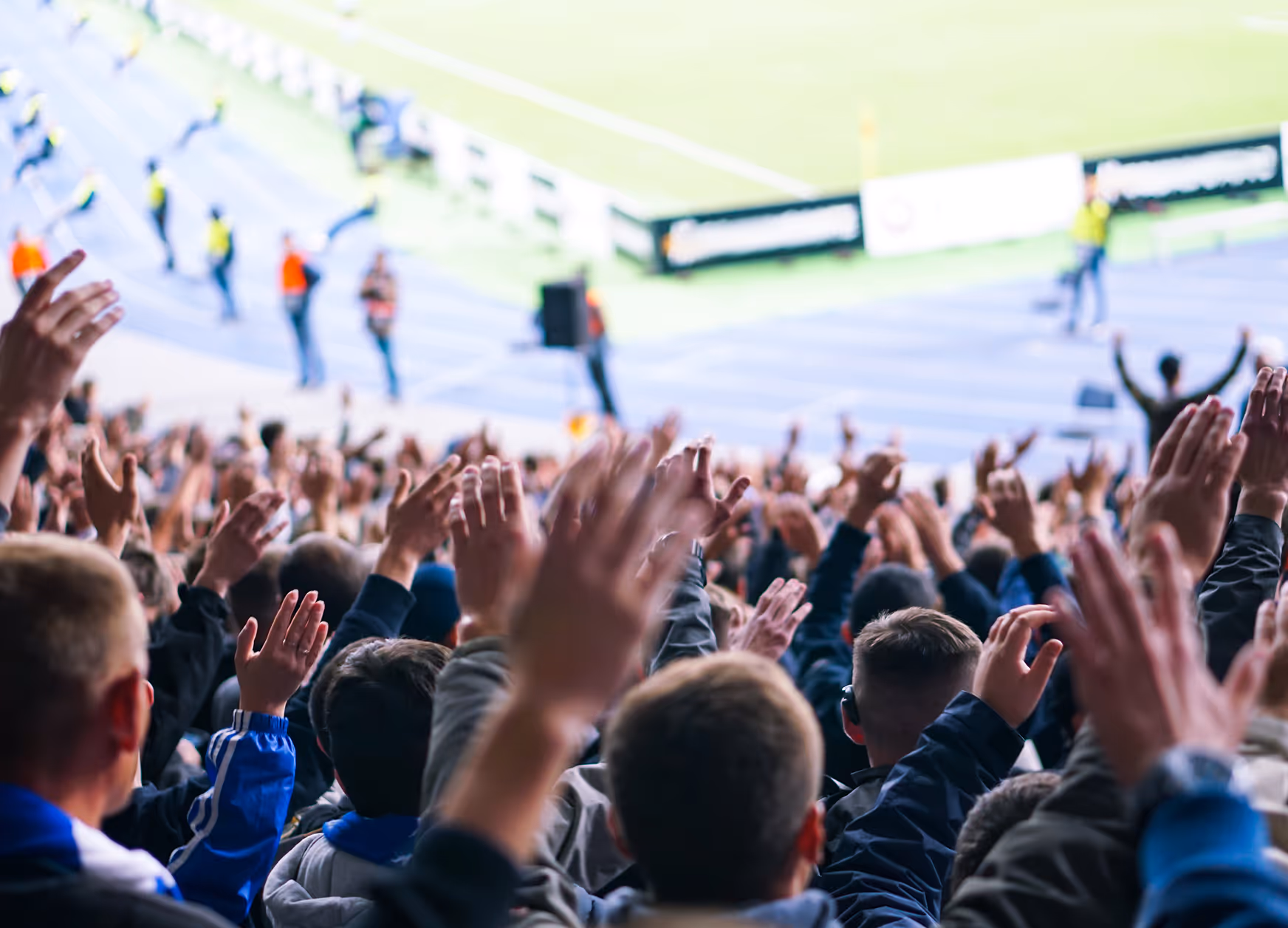 Jubelnde Menschenmenge bei einer Veranstaltung, die Hände in der Luft.