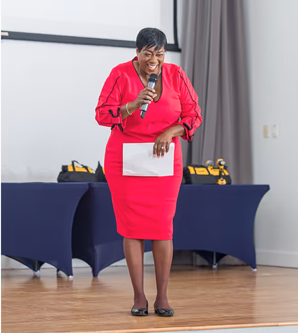Woman in red dress speaks on stage at Overtown Performing Arts Center event
