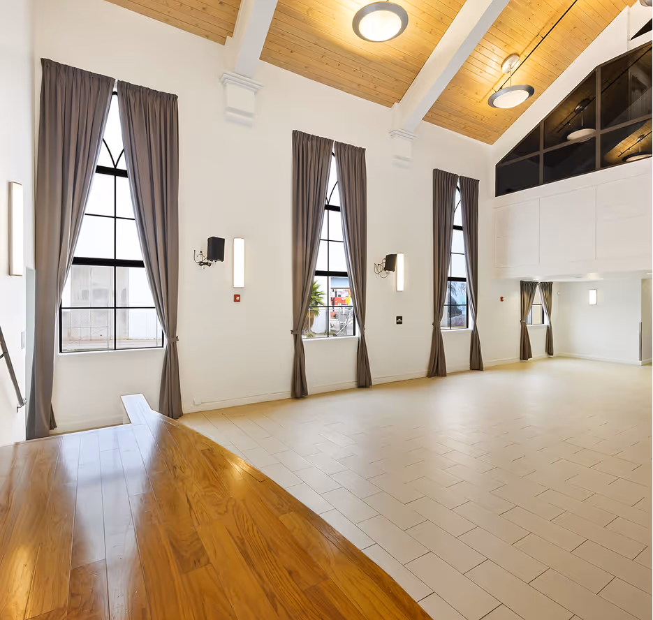 Sunlit Overtown Performing Arts Center hall with tall windows and wood ceiling
