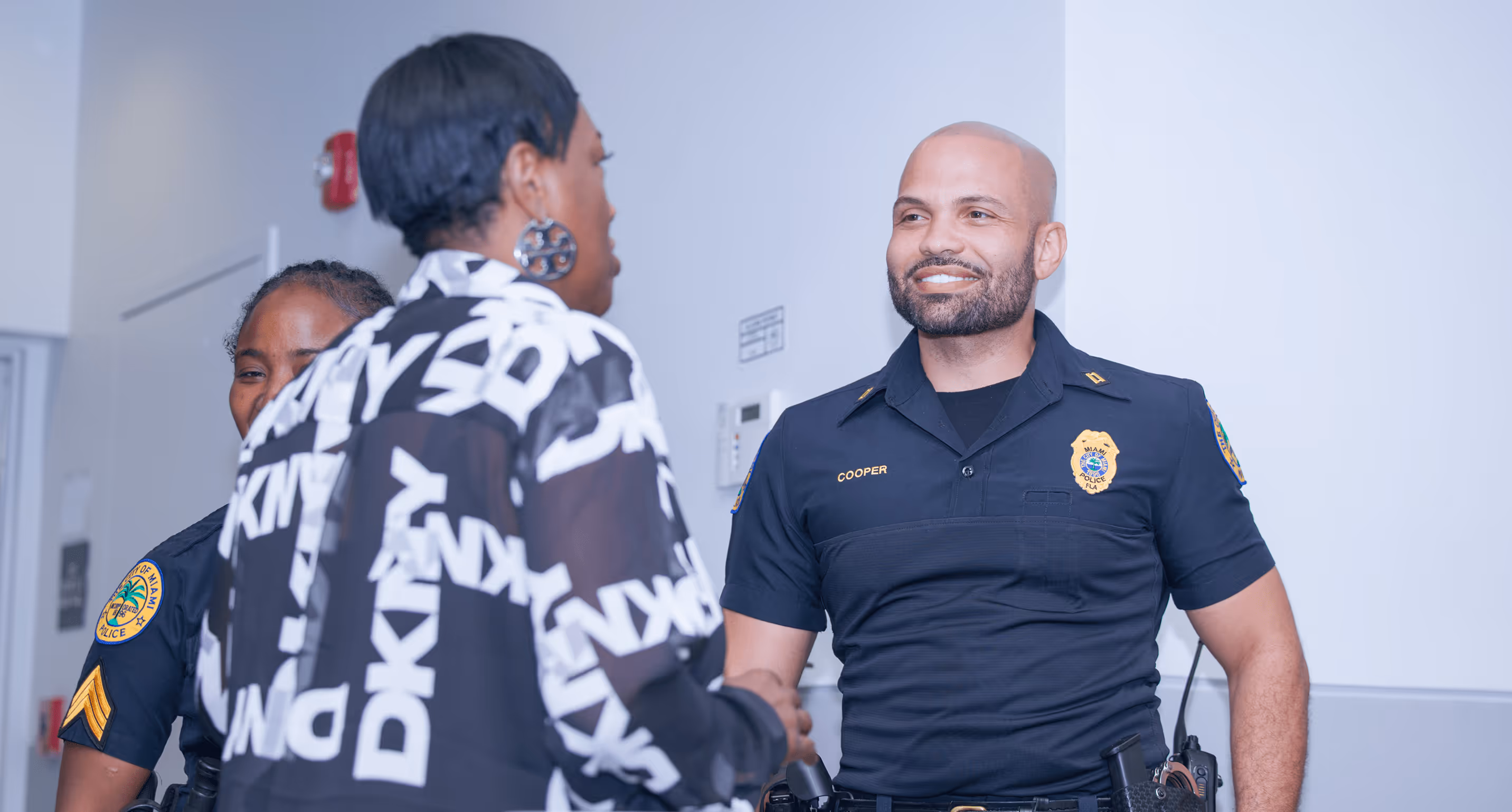 Smiling Miami police officer greets attendee at Overtown Performing Arts Center community event