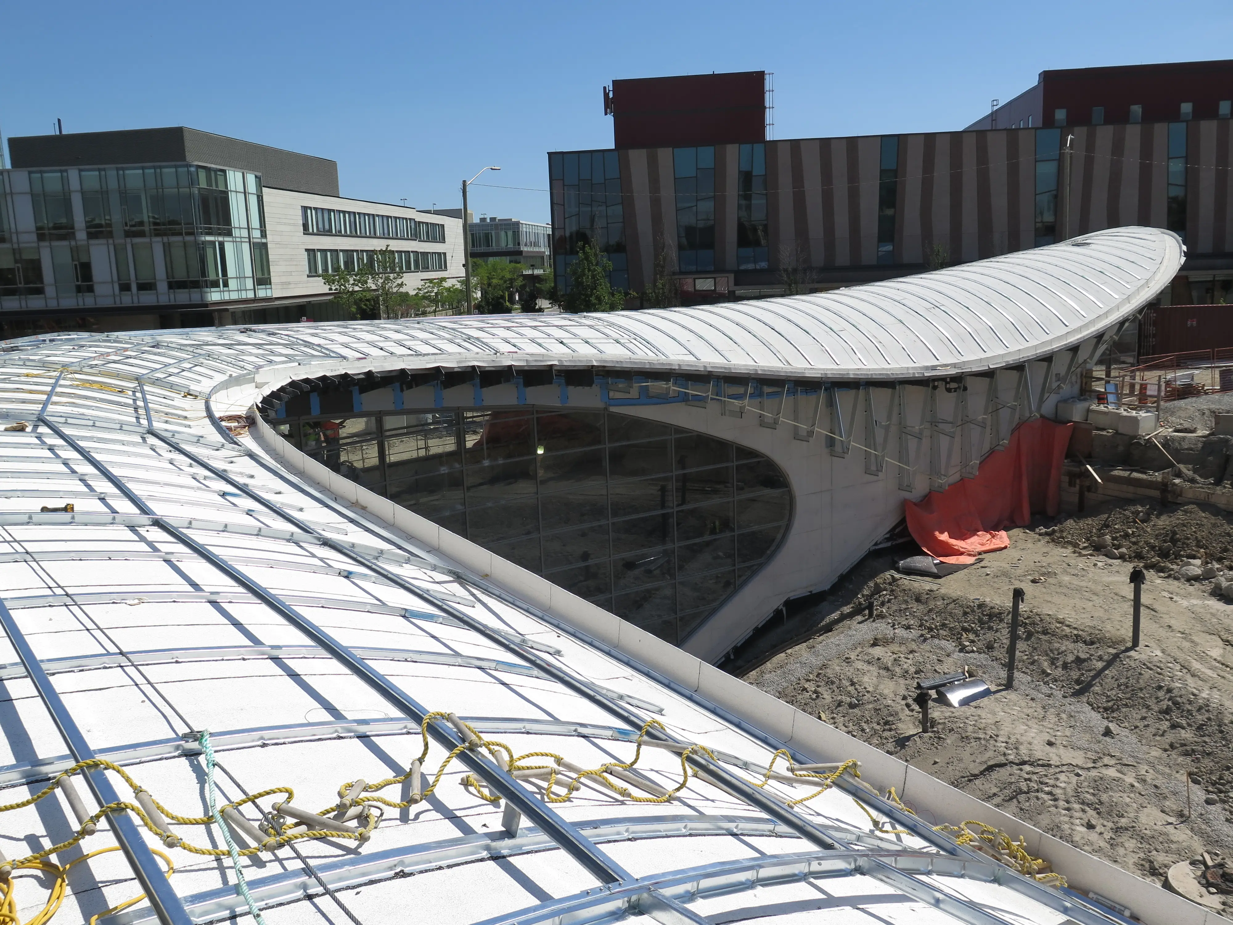 Curved roof structure under construction, with exposed framing and an oval roof opening that highlights the panelized, doubly curving geometry.