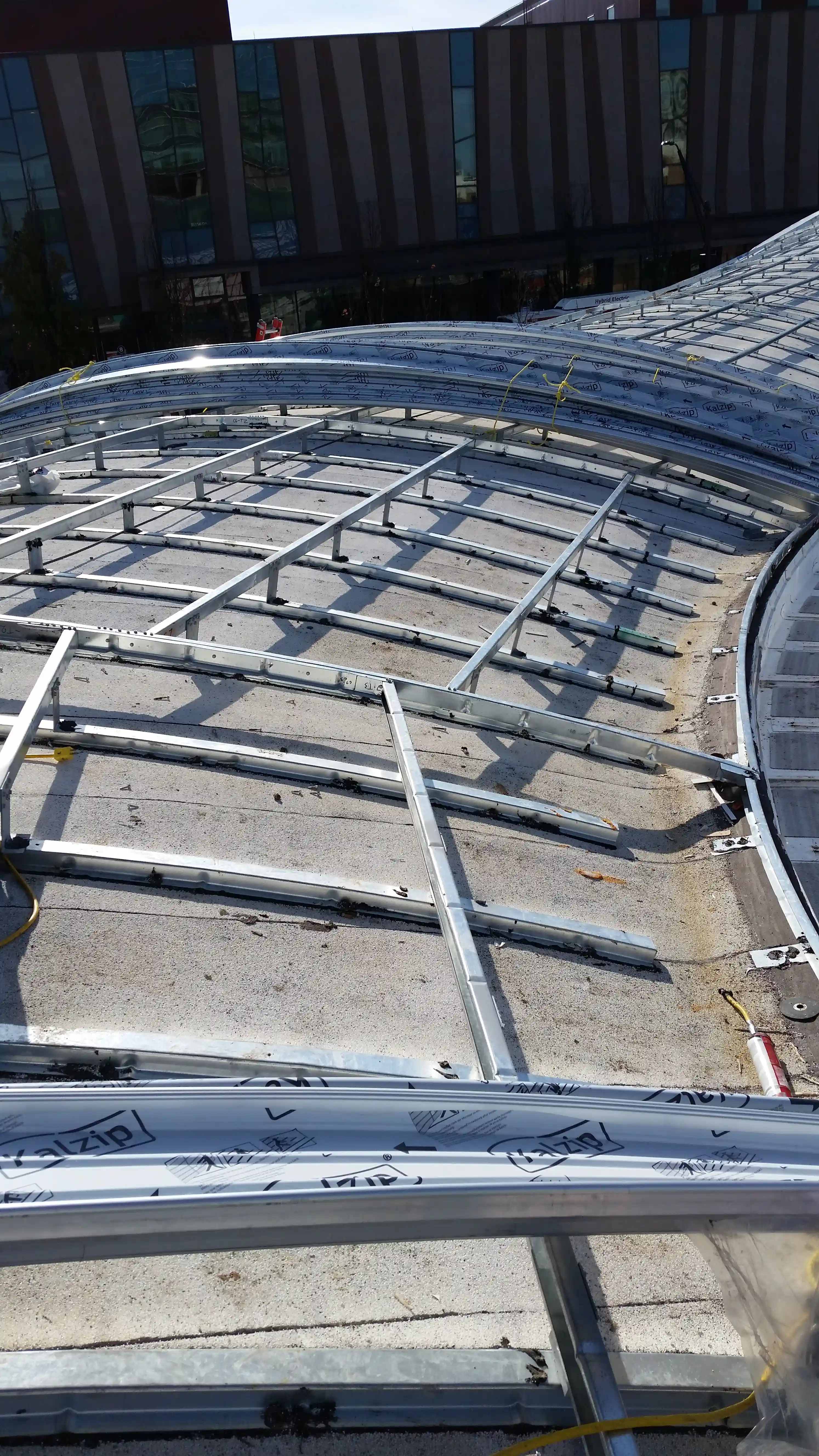 Curved metal roof framing set off the roof deck with clips and arranged to define the compound roof form.