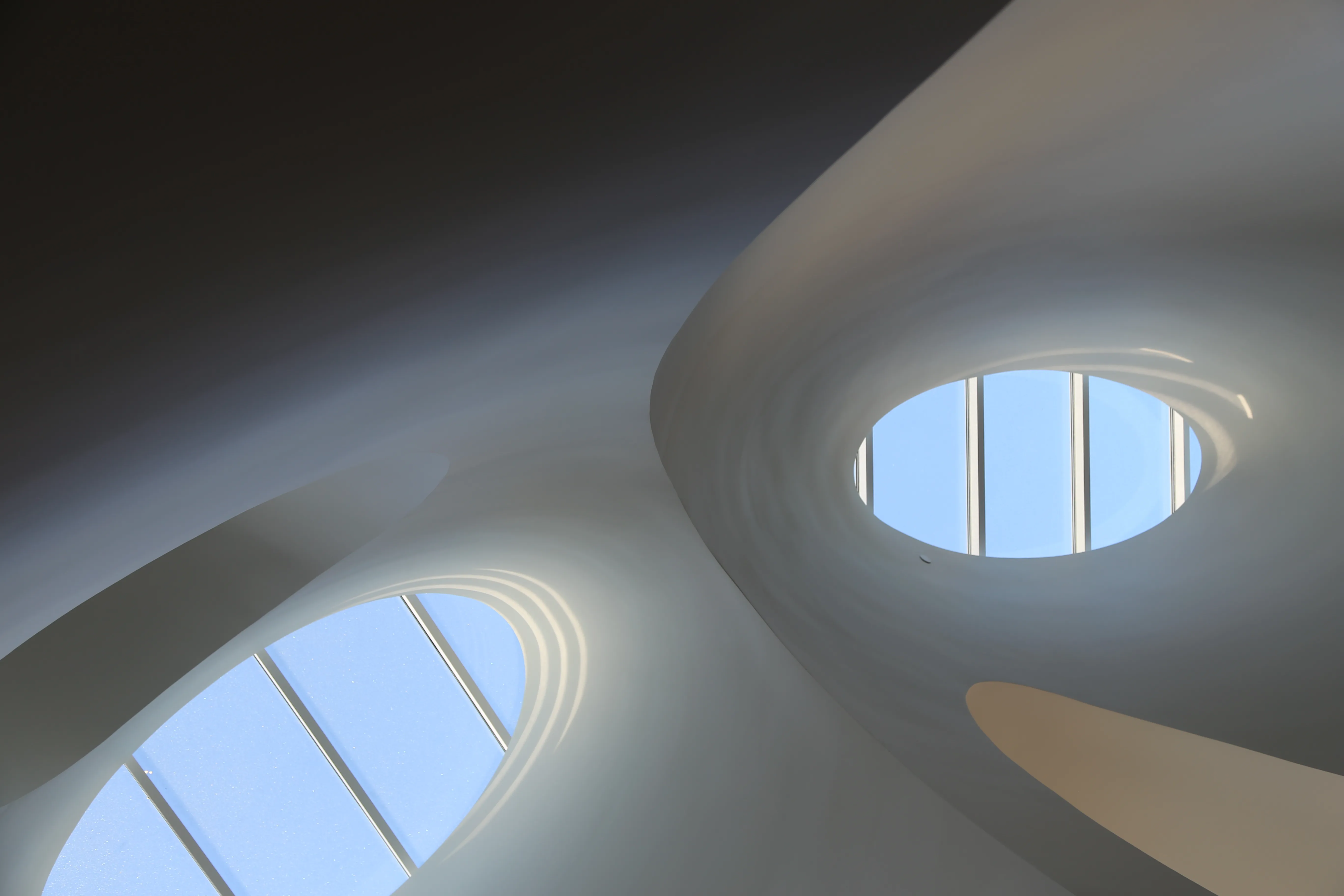 Curved cold formed metal framing grid with circular skylight openings forming compound ceiling geometry at Hill House