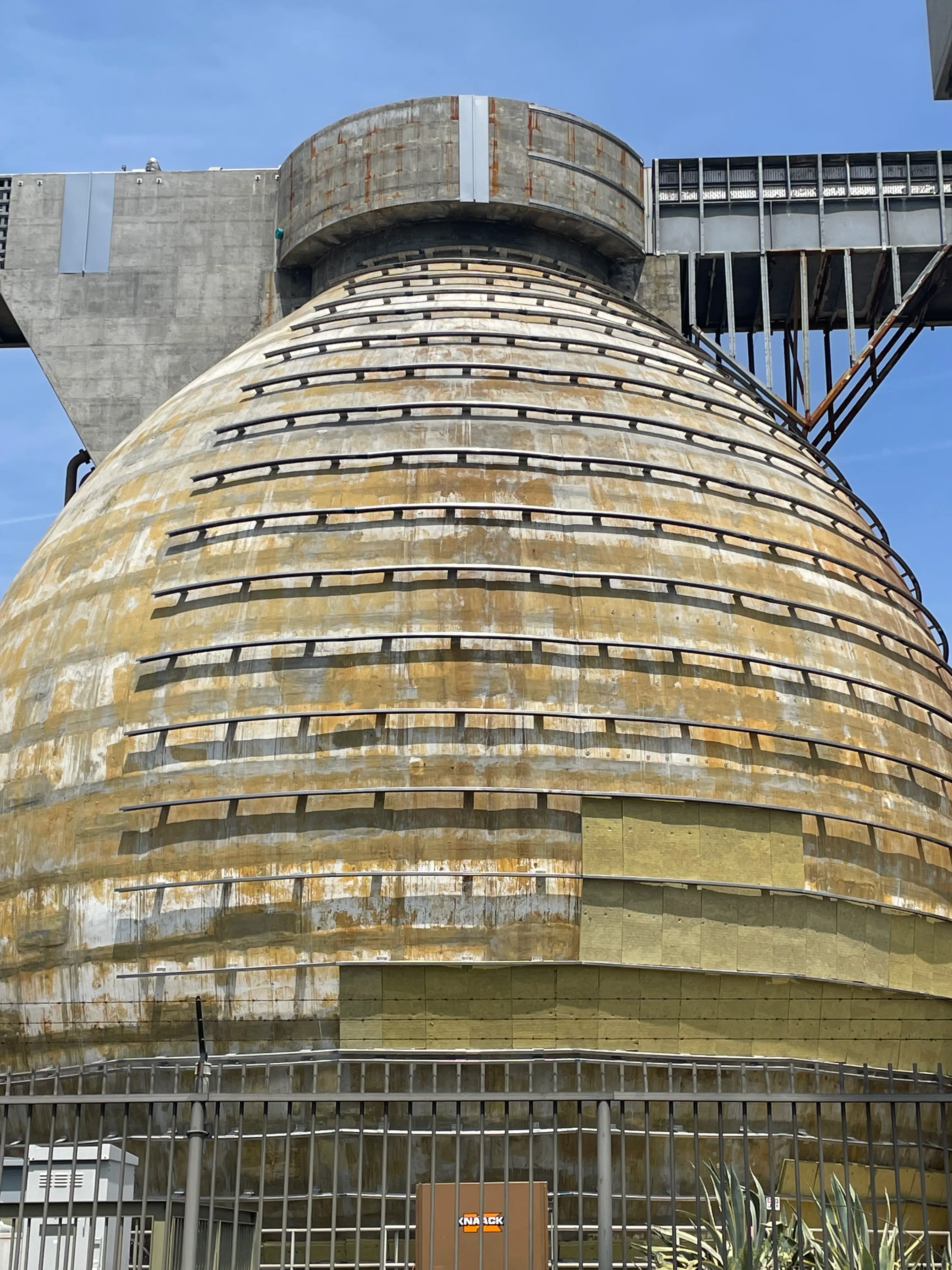 Curved clip and rail system with insulation installed over spherical concrete digester prior to metal panel cladding