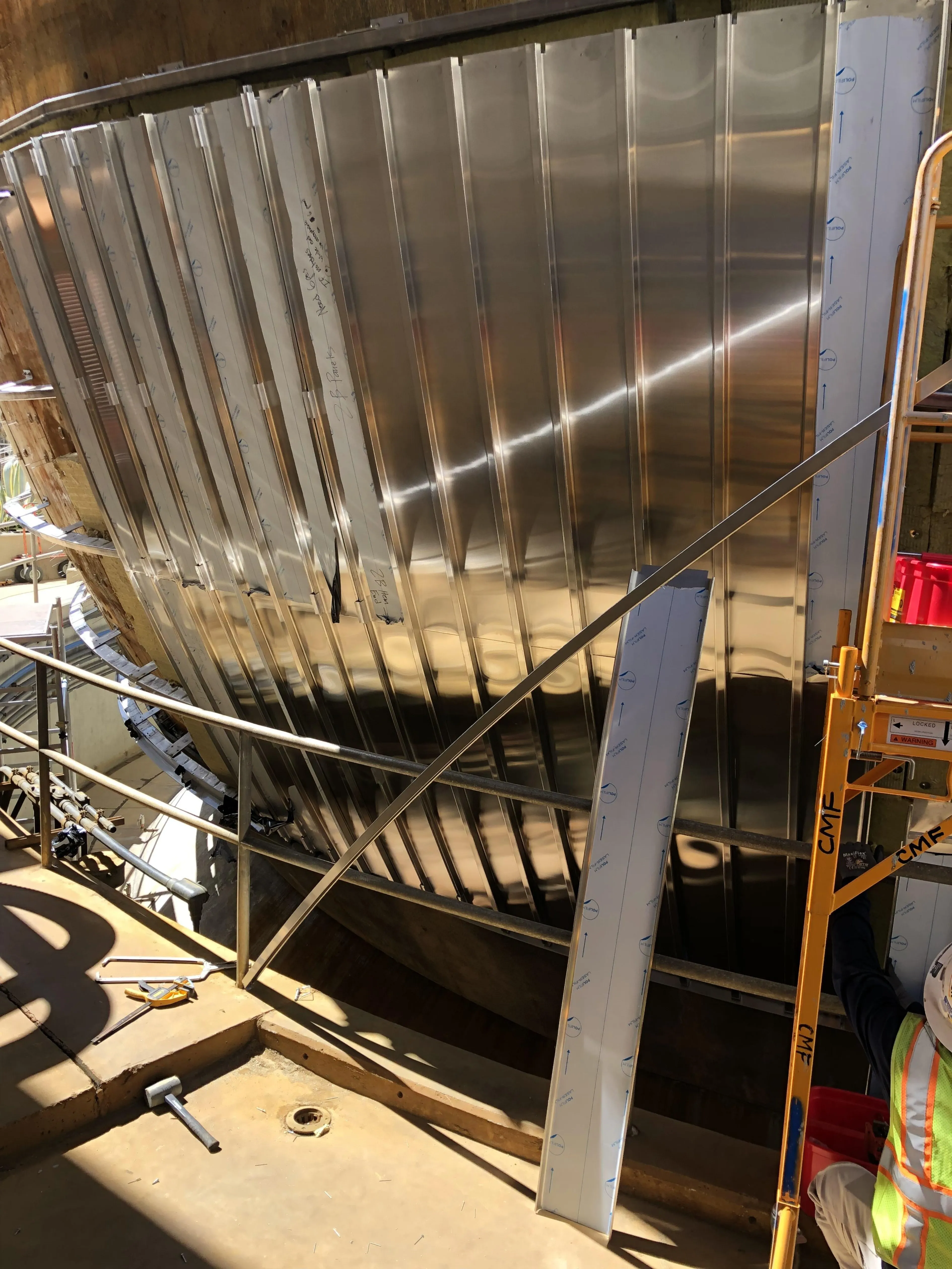 Curved stainless steel panels being installed on spherical digester using precision framing and support system