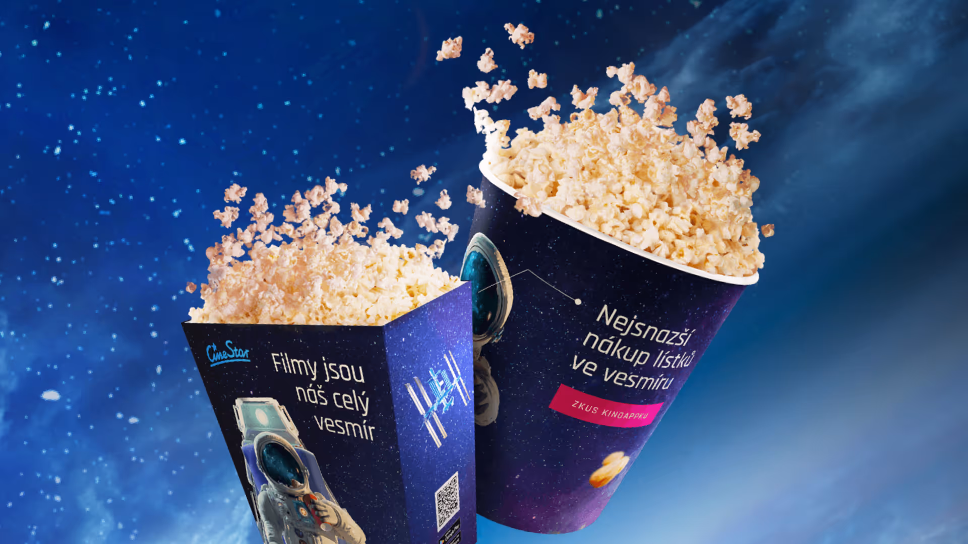 Two popcorn containers filled with popcorn floating in a starry space background, one container shows an astronaut and Czech text promoting movie tickets and CineStar.