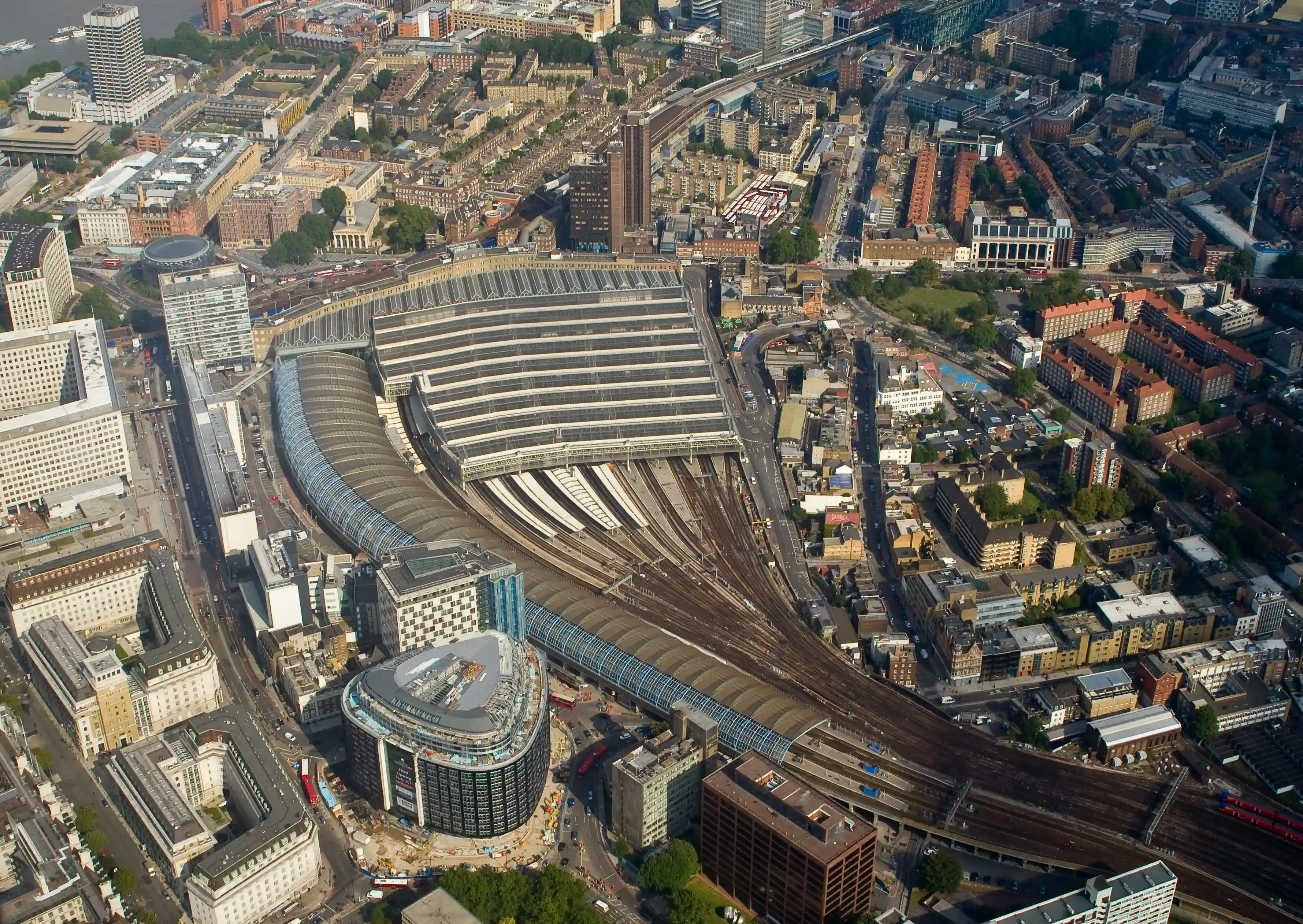 Aerial view of London Waterloo train station with multiple train tracks, platforms, and surrounding urban buildings.