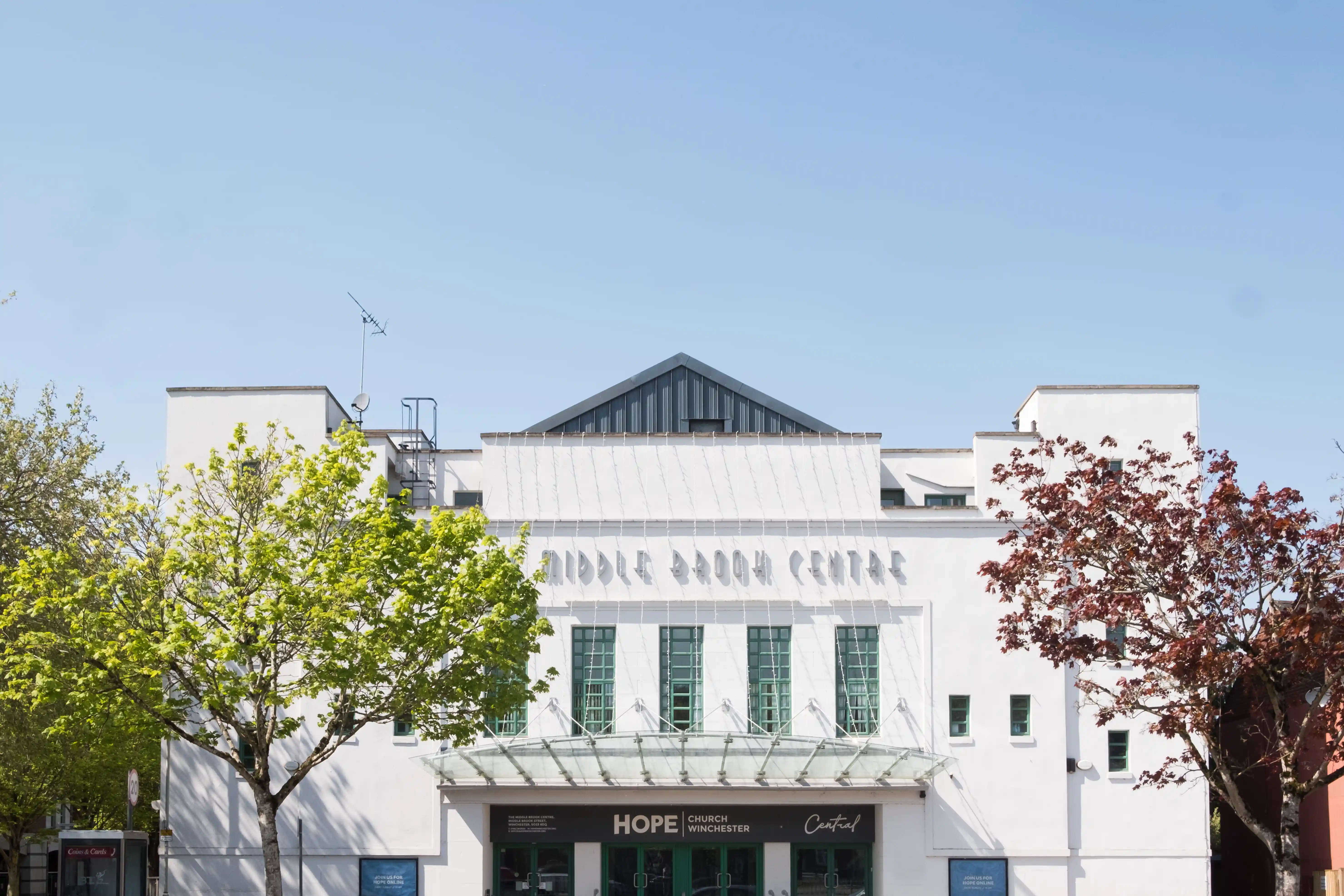 White modern building with green windows and entrance labeled 'HOPE Church Winchester' under a clear blue sky.