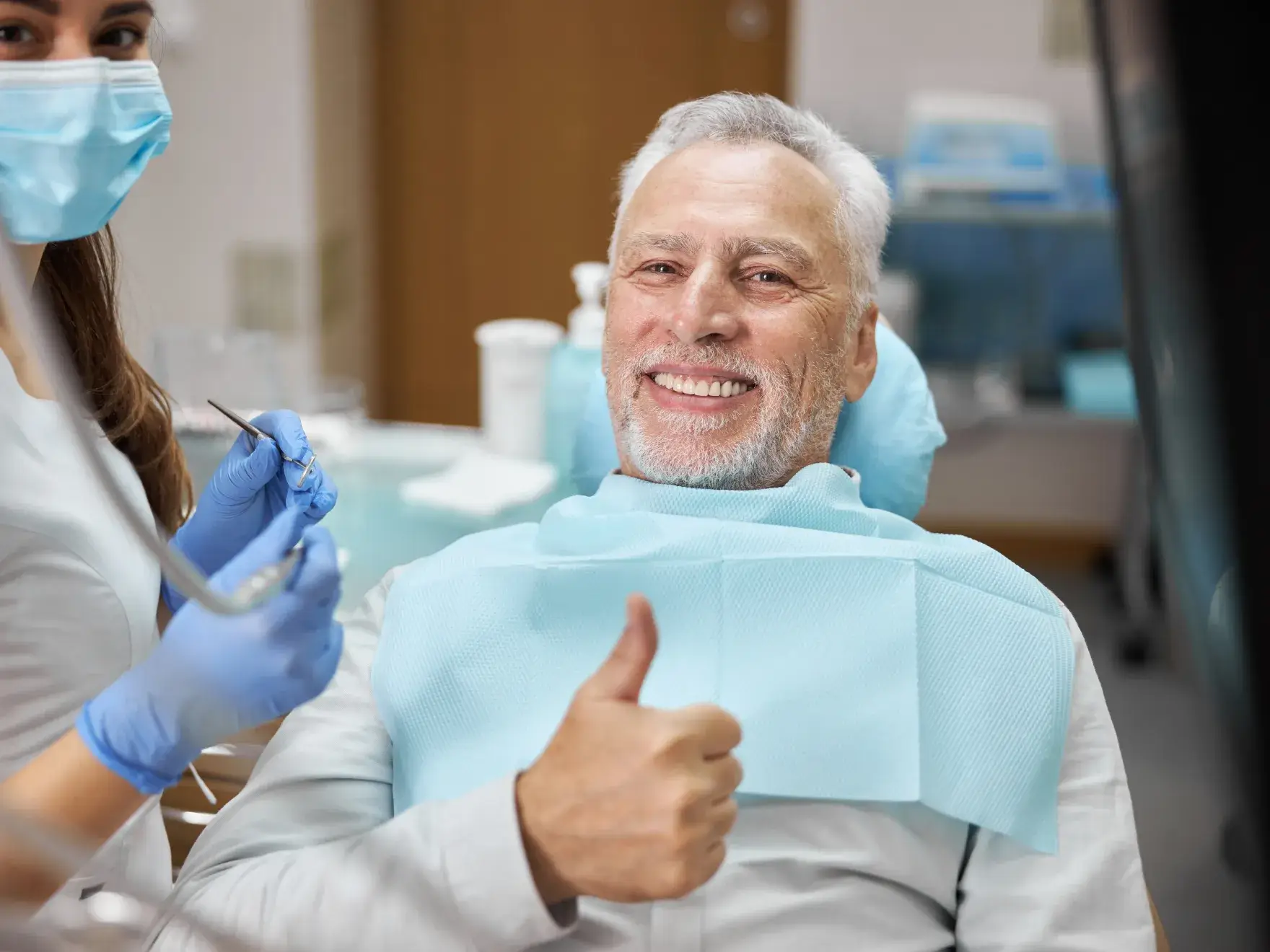 A man in a dentist chair giving a thumbs up.
