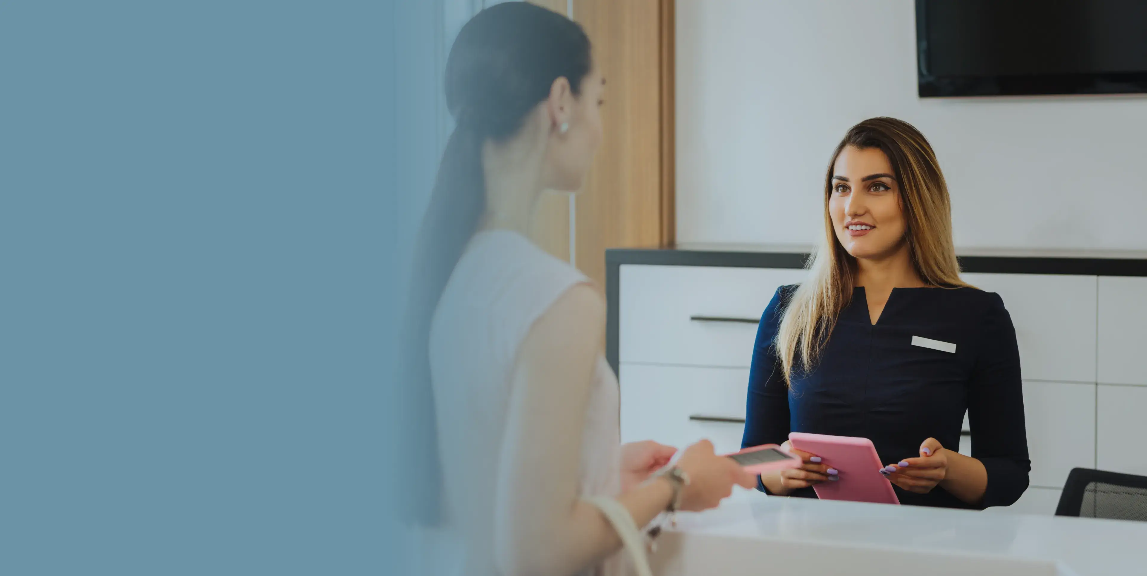 A woman talking to another woman at a desk.