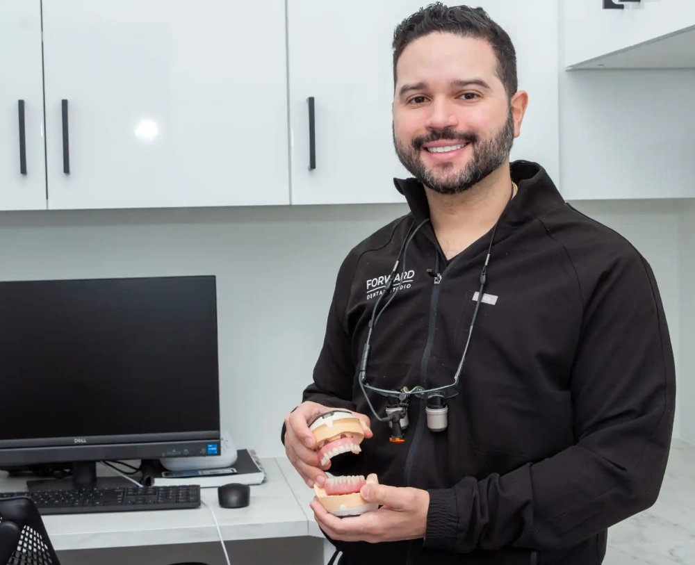 Dr Luis Peralta showing a model of dental implants