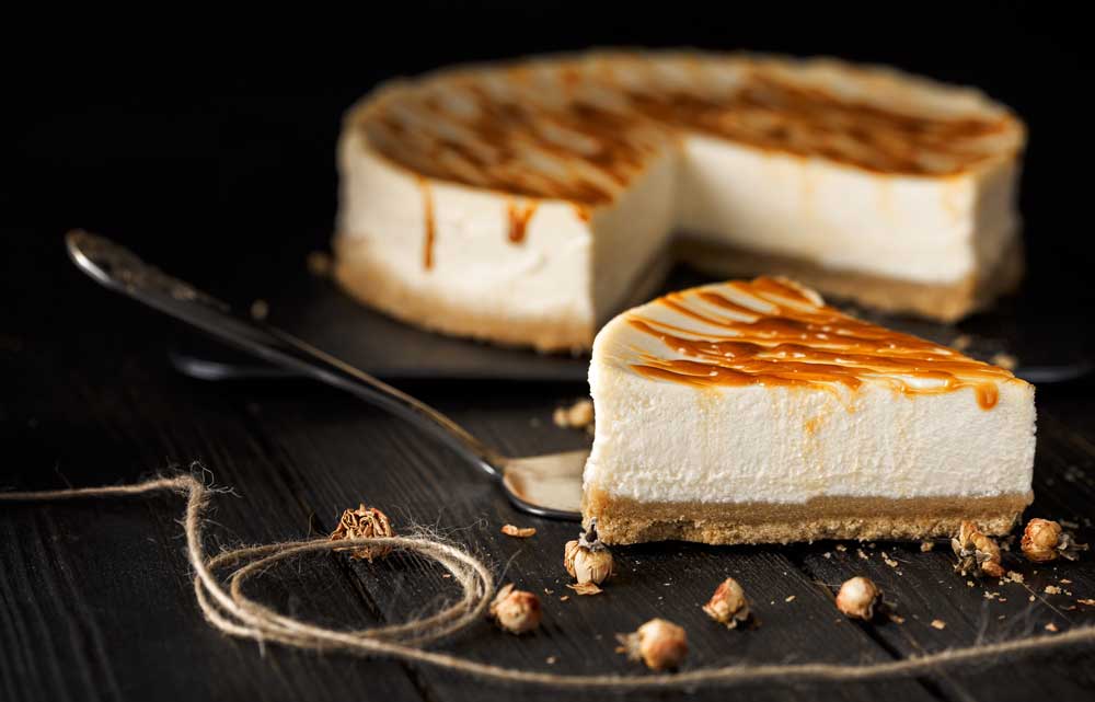 A slice of cheesecake with caramel drizzled on top.