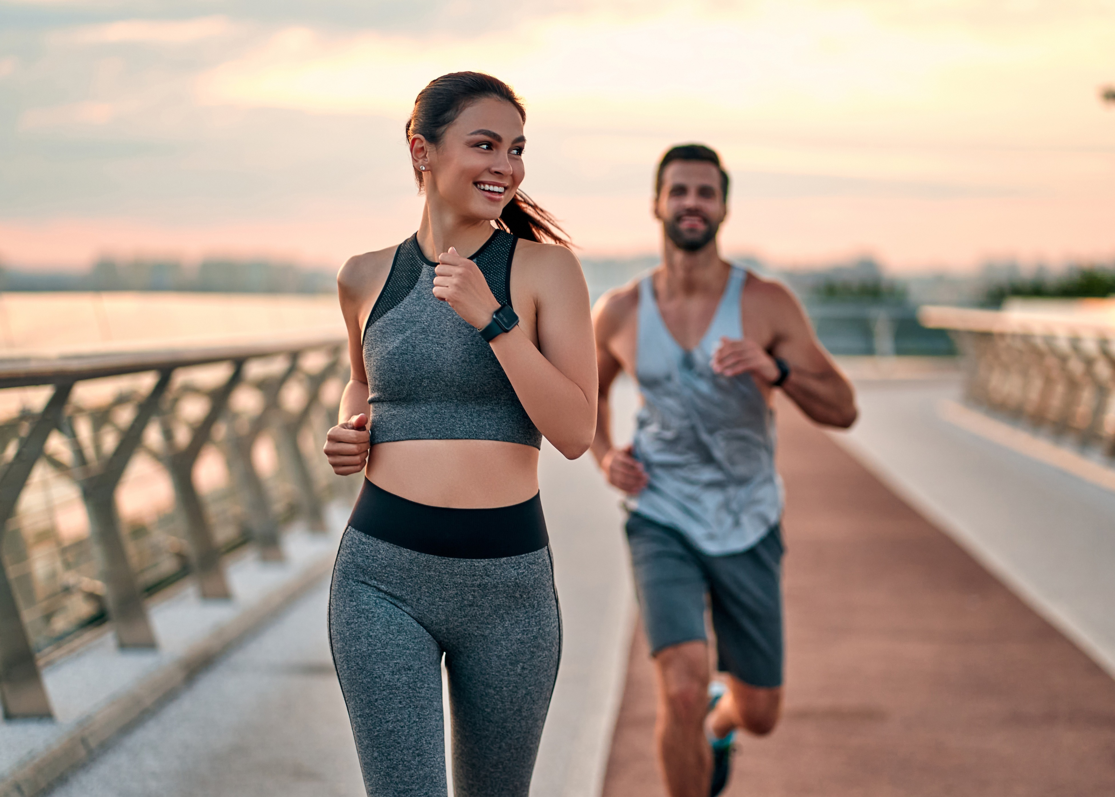 A man and a woman running on a bridge.