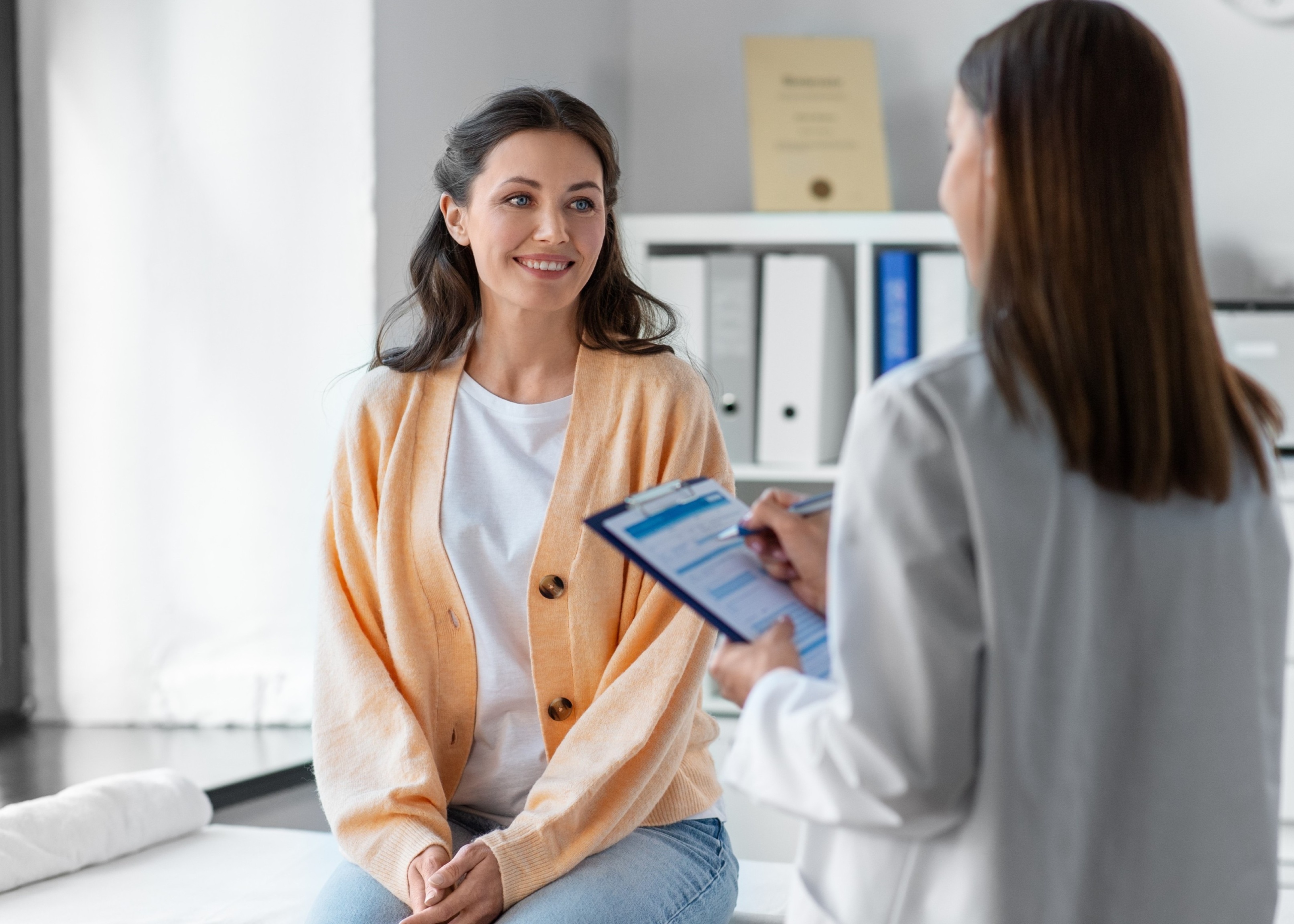 A woman sitting on a table talking to another woman.