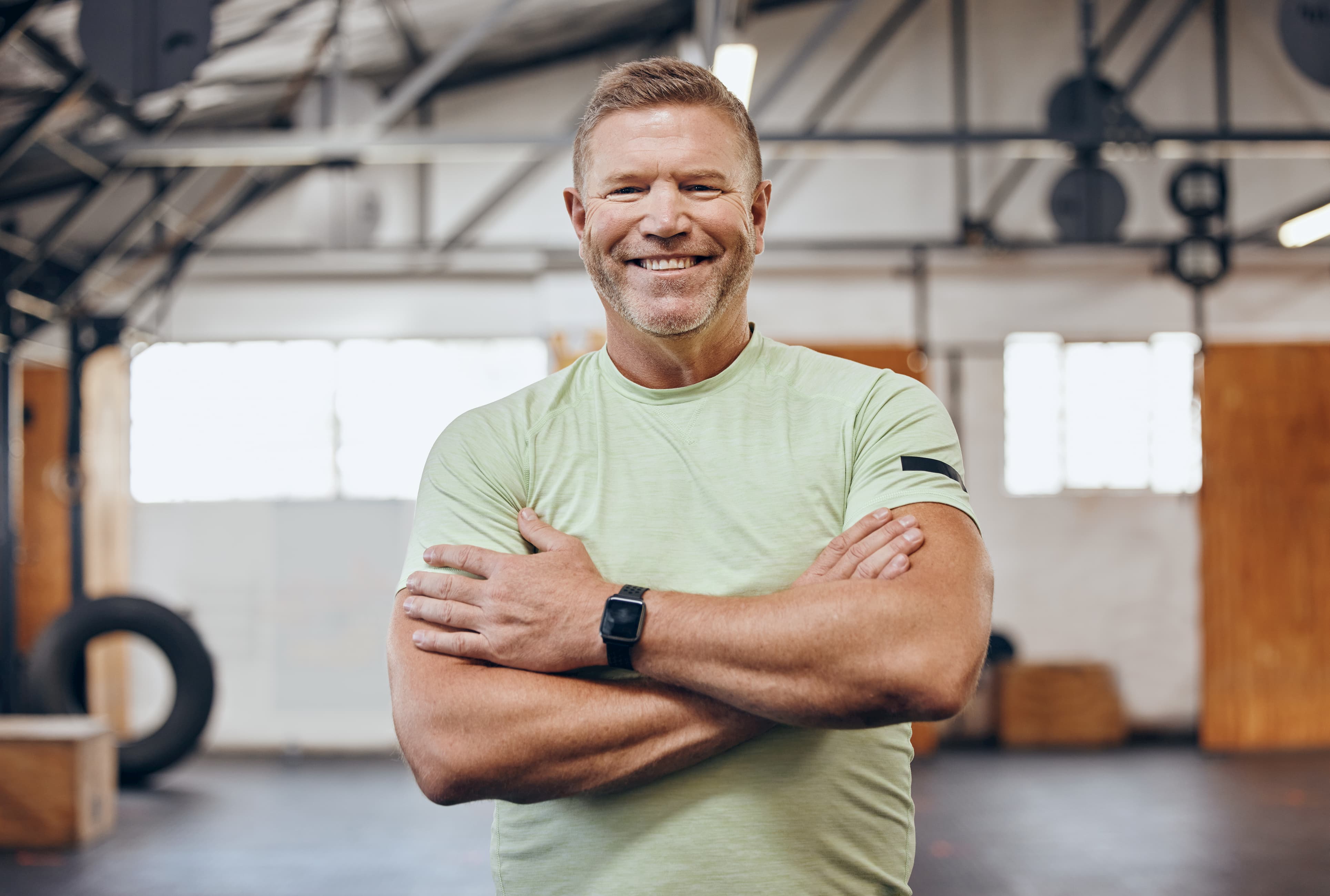 A man standing in a gym with his arms crossed.