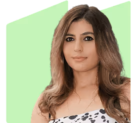 KUGU Mitarbeiterin Lilit, eine junge Frau mit langem braunem Haar und schwarzem gepunktetem Top vor grünem Hintergrund.