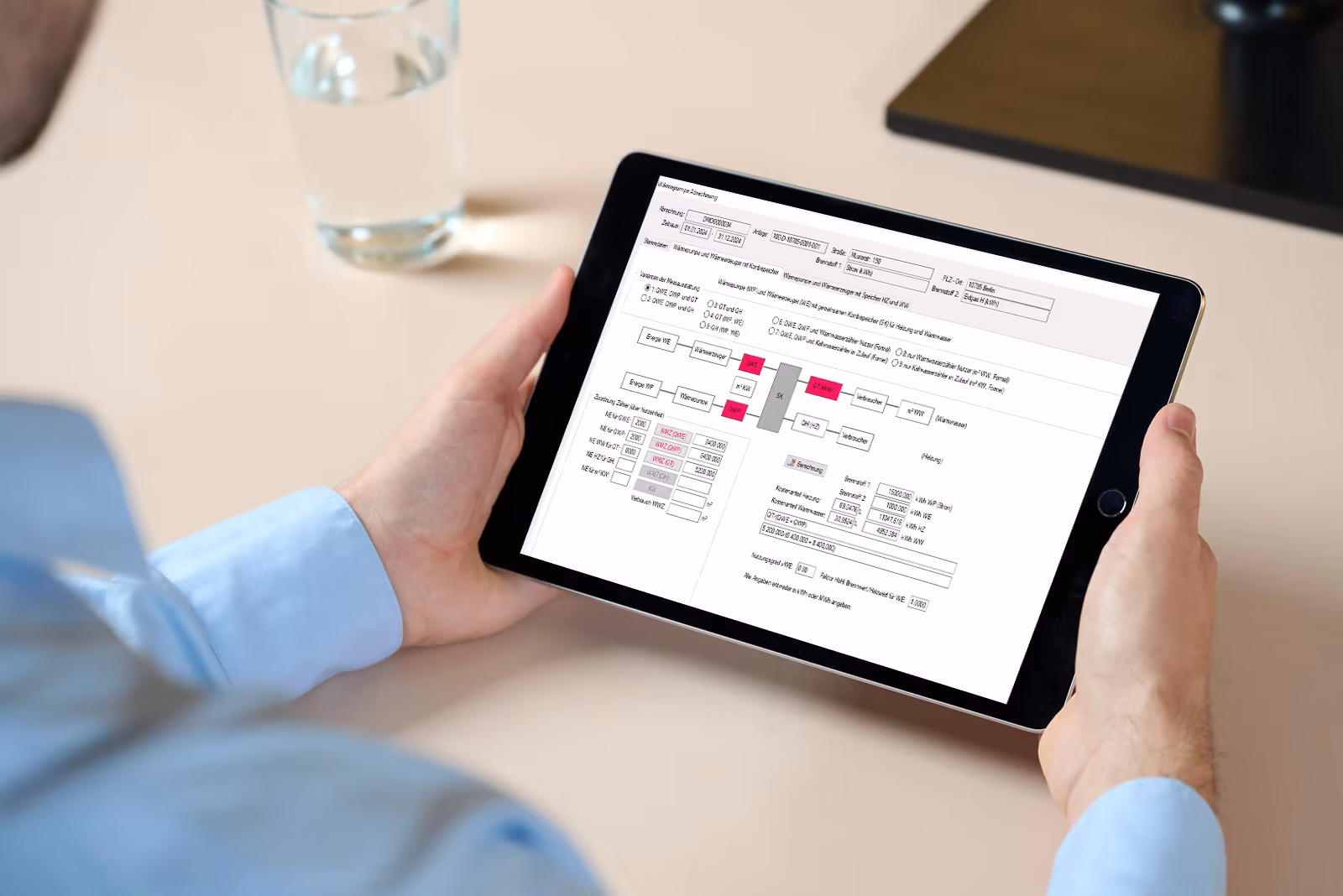 Person hält ein Tablet, das einen Bildschirm von KUGU AbSys zeigt, einer All-in-one Software für Abrechnung, Wärmemengenerfassung und Heizungsdaten.