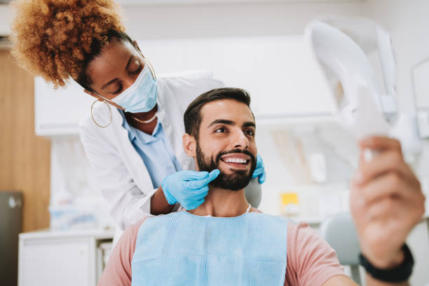 Man dental treatment with woman dentist looking in mirror Man dental treatment with woman dentist looking in mirror guy at dentist smiling stock pictures, royalty-free photos & images
