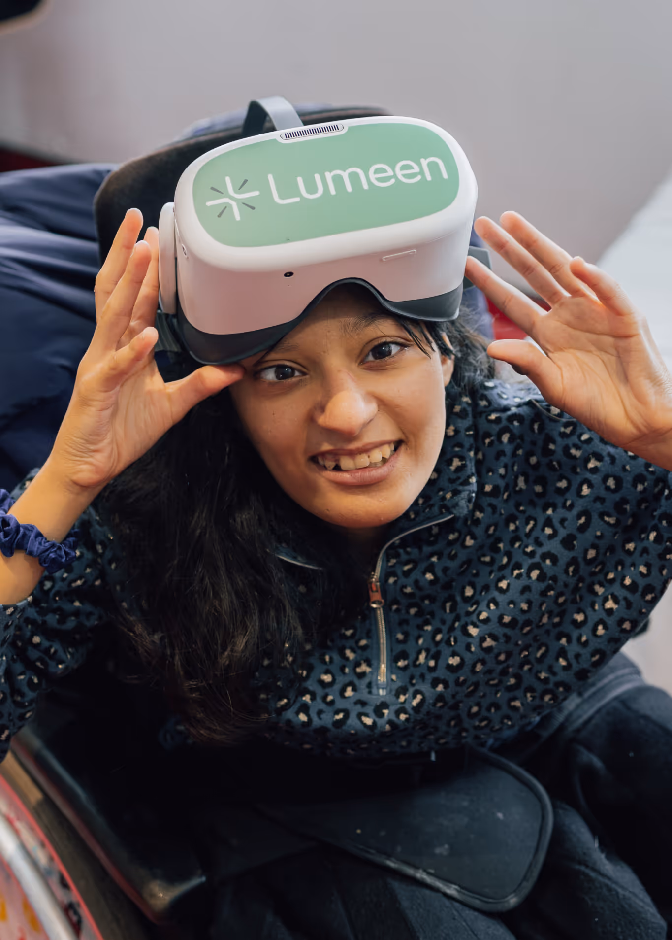 Résidente âgée en fauteuil, casque VR Lumeen, accompagnée par une soignante qui tient sa main pendant la séance.