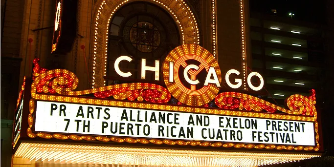 The illuminated Chicago Theatre marquee at night announcing the 7th Puerto Rican Cuatro Festival presented by Puerto Rican Arts Alliance and Exelon.