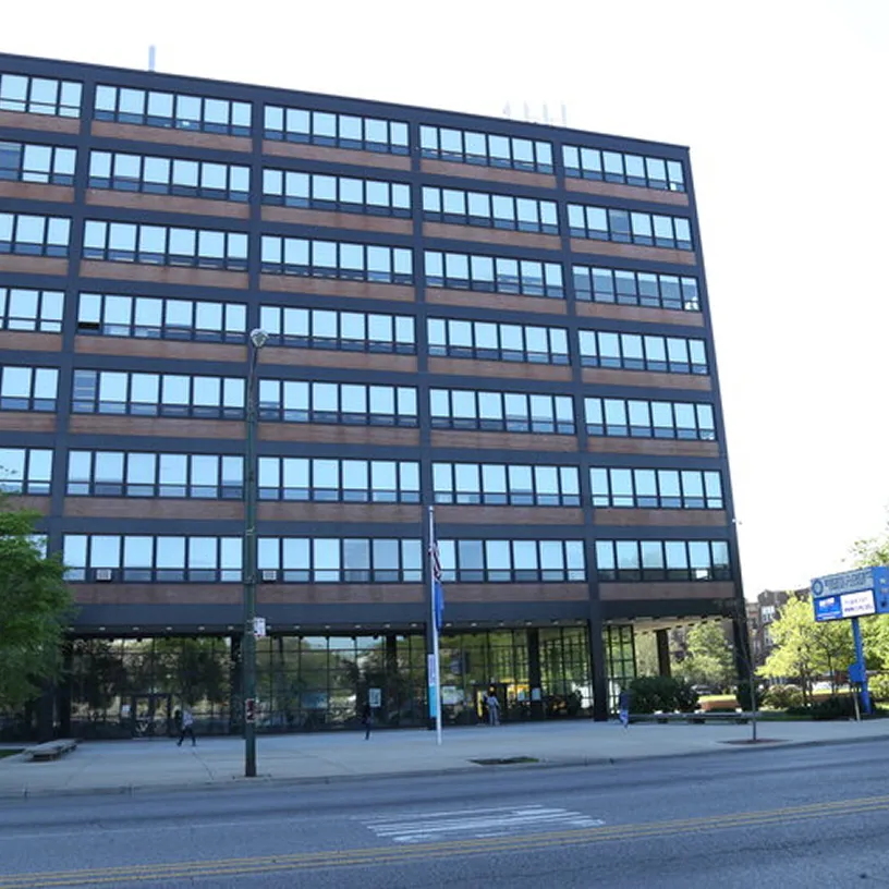 Multi-story office building with rows of windows and glass entrance facing a city street.