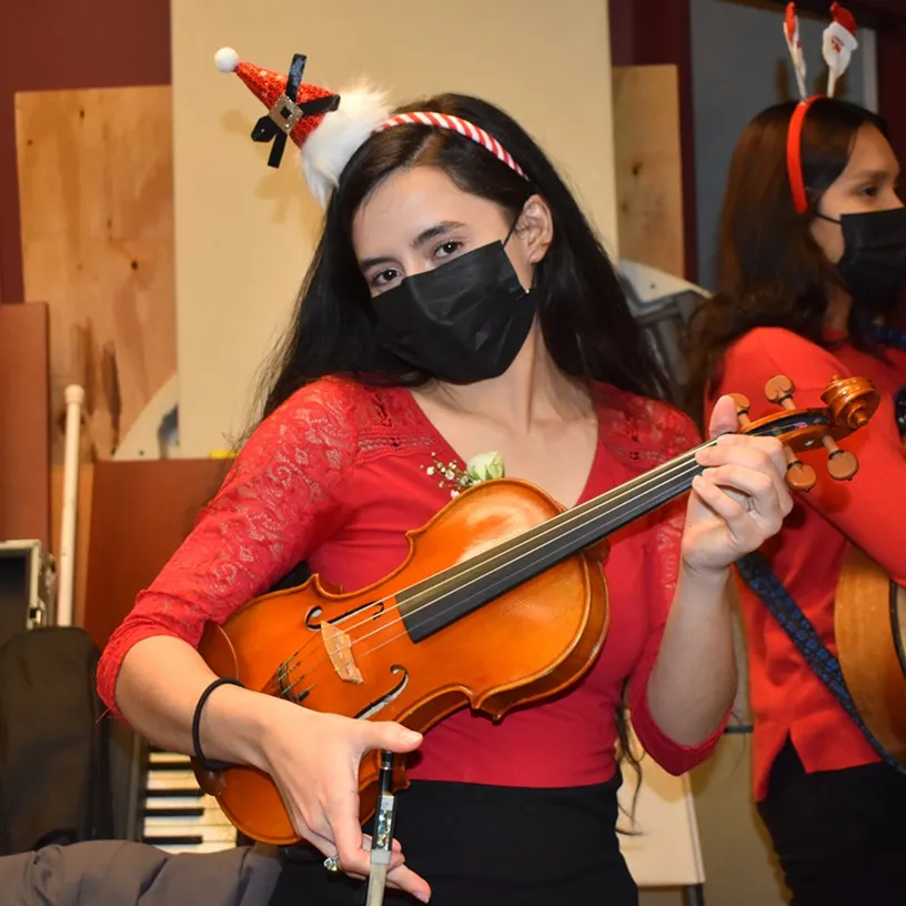 Young woman wearing a red dress and a festive Santa hat headband.