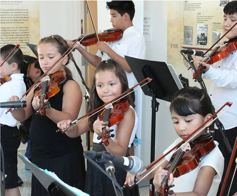 Group of children playing violins together in a musical performance setting.