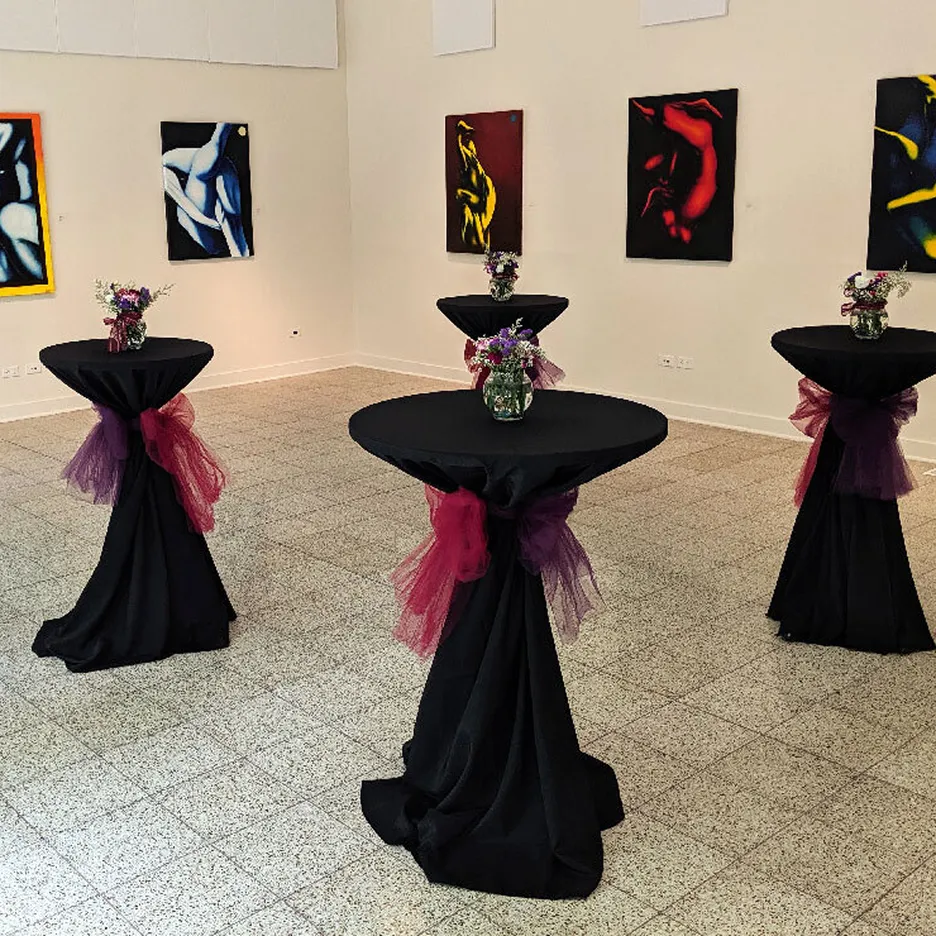 Gallery room with four cocktail tables draped in black cloths tied with purple and red tulle, each adorned with small flower arrangements, and abstract paintings on the walls.