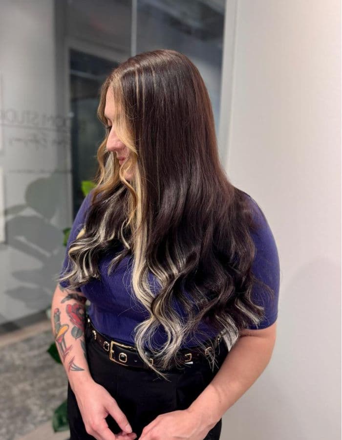 Brunette with long wavy Ice Fusion Hair Extensions and highlights in Houston salon.