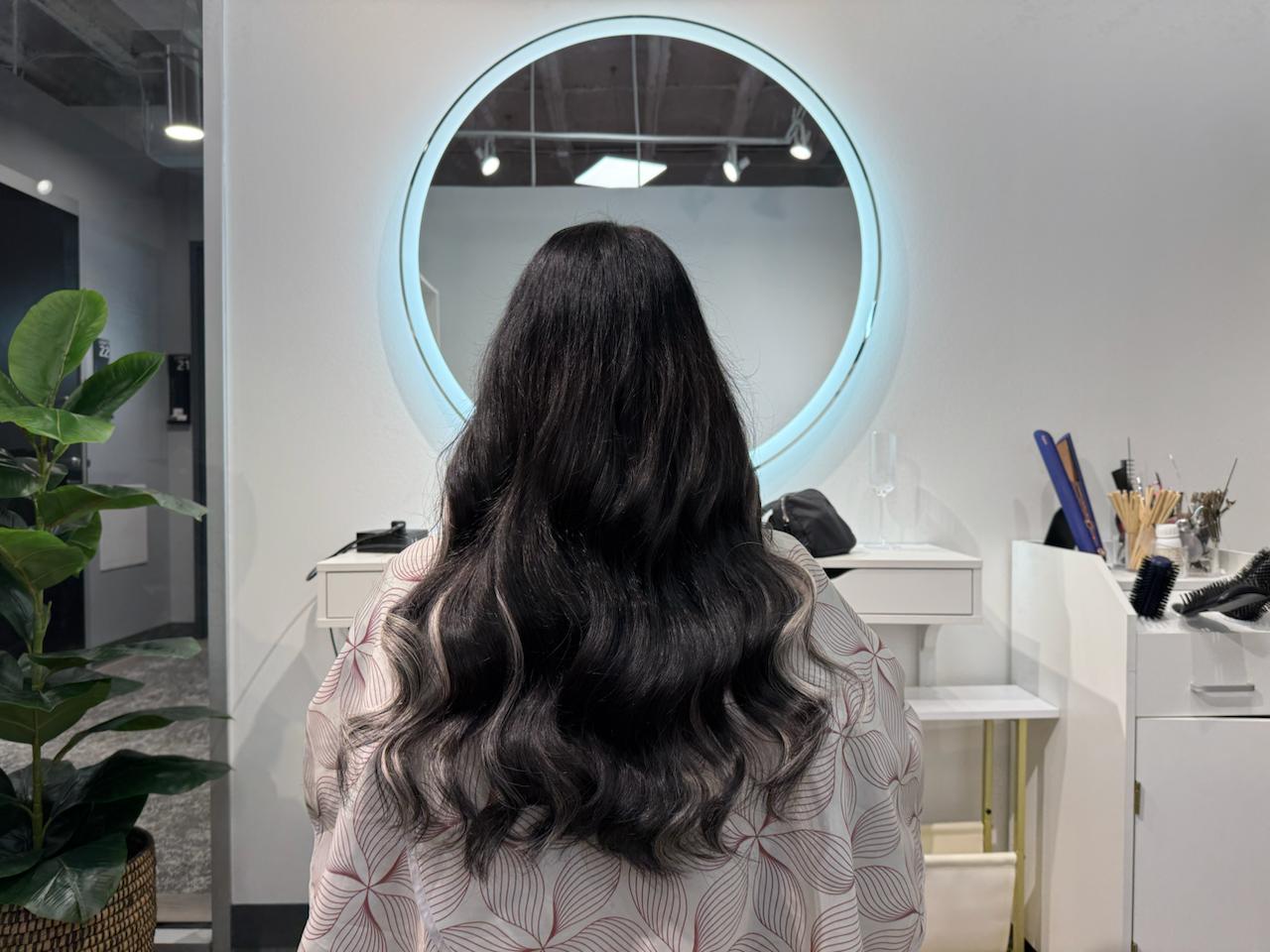 Stylist at Bloom Studio Hair Extensions in Houston performing a deep repair treatment on long Ice Fusion hair extensions, showing gentle care and luxury salon atmosphere.