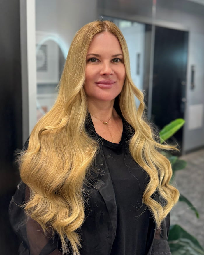 Front view of long blonde Ice Fusion hair extensions with soft waves by Bloom Studio Hair Extensions in Houston