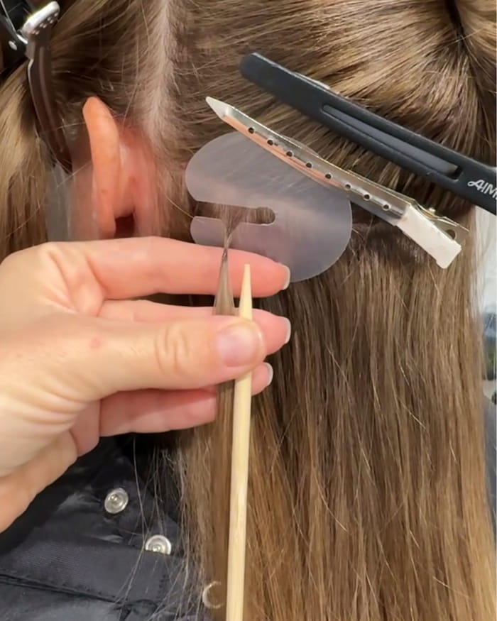 Close-up of invisible Ice Fusion micro-bond being applied strand by strand at Bloom Studio Hair Extensions in Houston