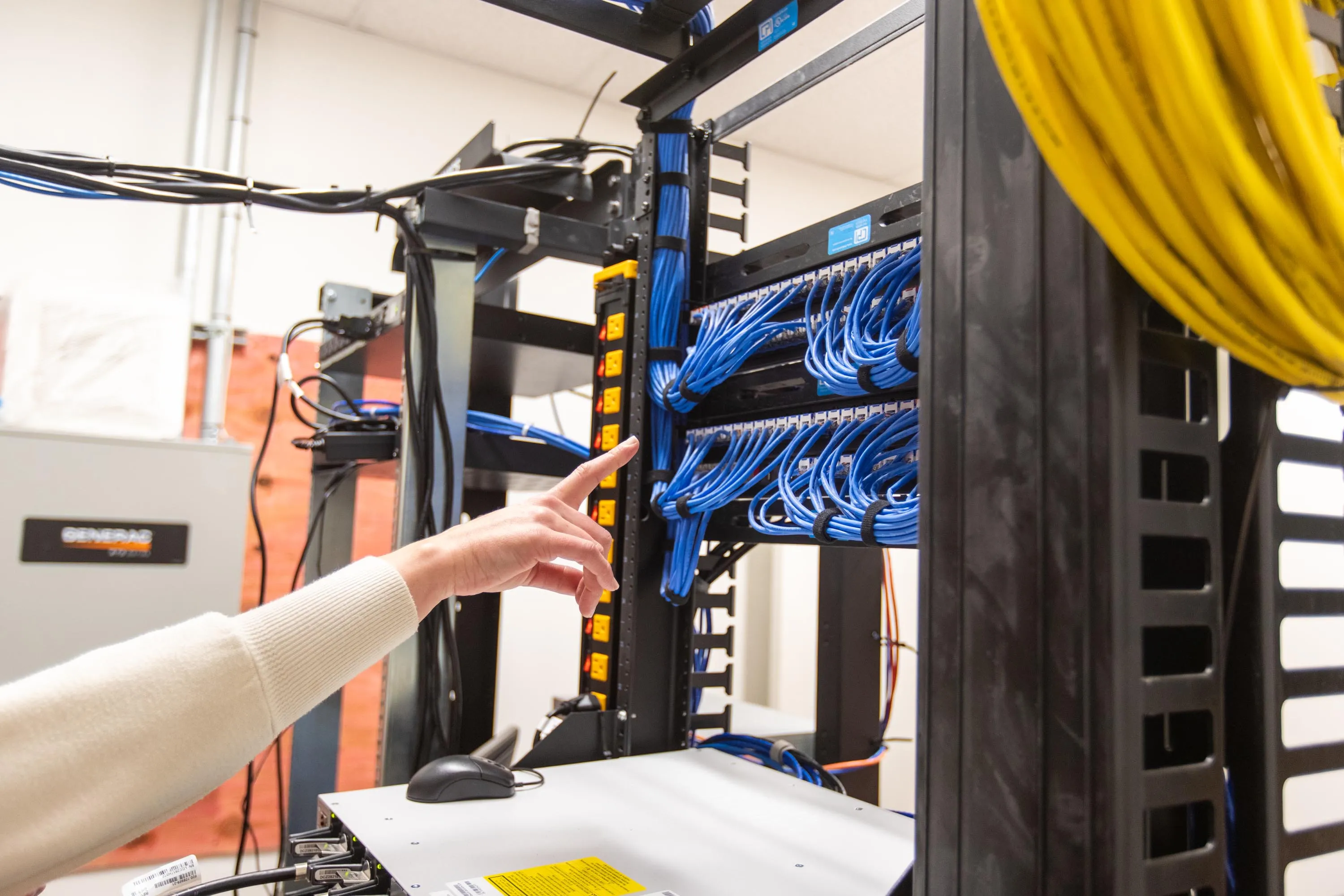Technician checking rack power distribution beside labeled patch panels