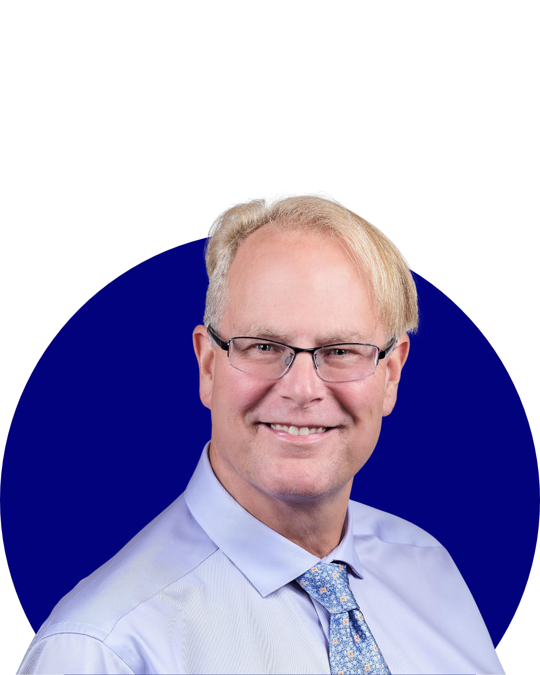 Smiling middle-aged man with glasses, blonde hair, light blue shirt, and patterned blue tie against a dark blue circle background.