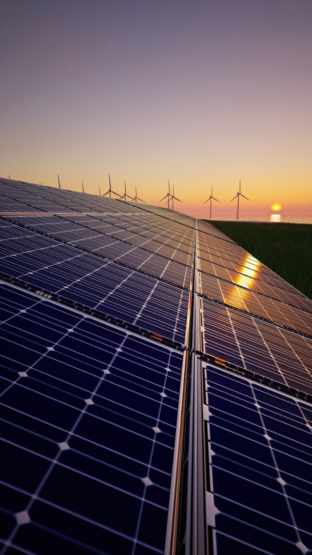 Solar panels and windmills in a sunset