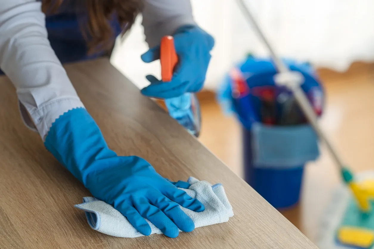 CloudClean professional wiping wooden surface with microfiber cloth and spray bottle during residential cleaning