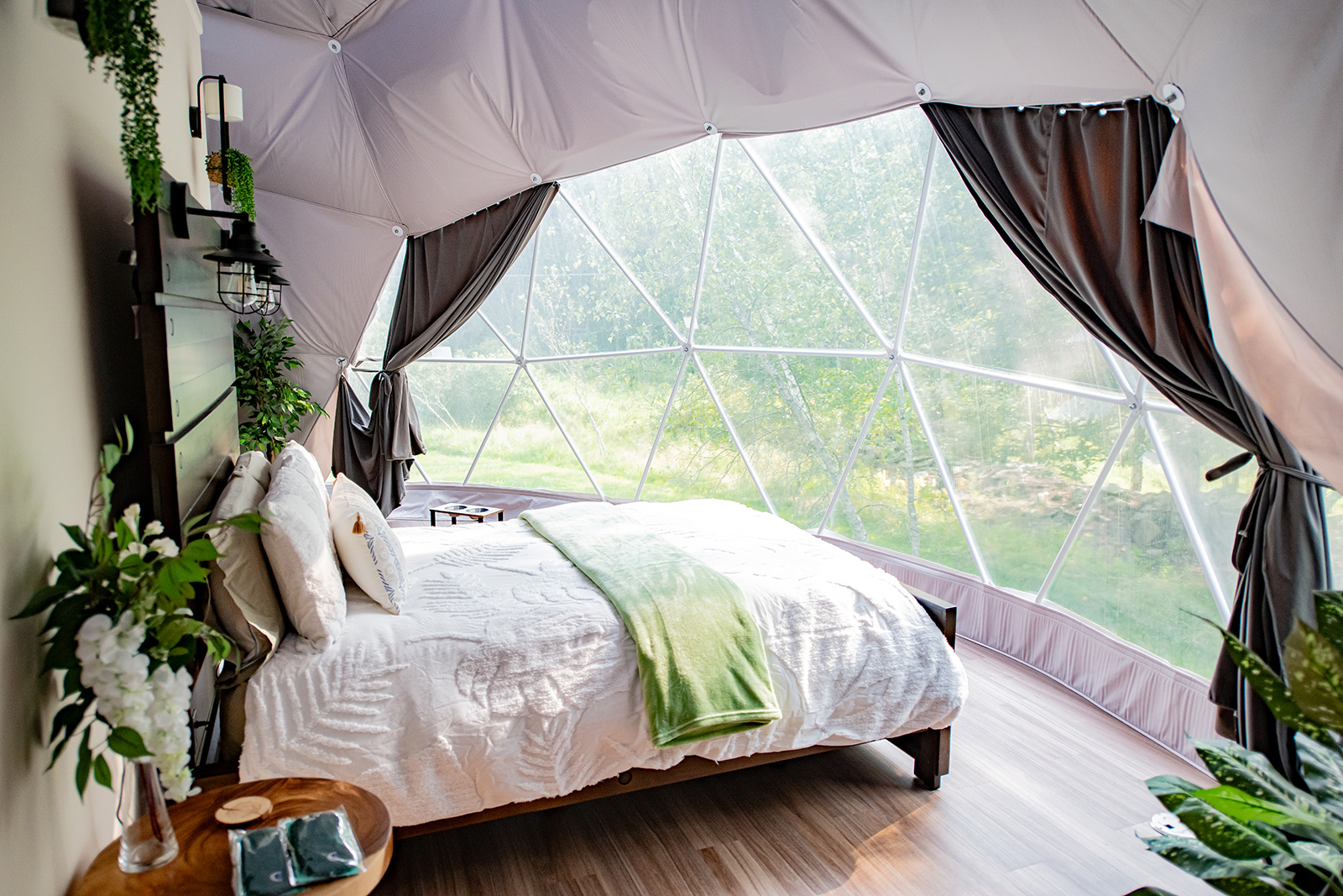 dome bedroom with large window overlooking greenery at Unique Escapes NY