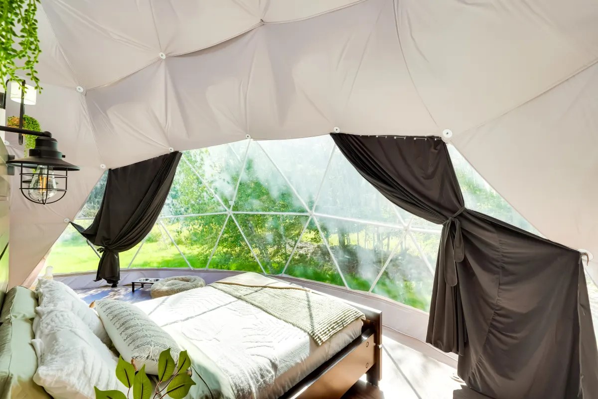 dome bedroom with open curtains and forest view at Unique Escapes NY