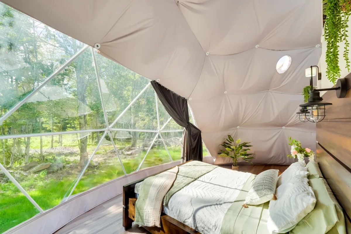 cozy bed with green view through the dome window at Unique Escapes NY